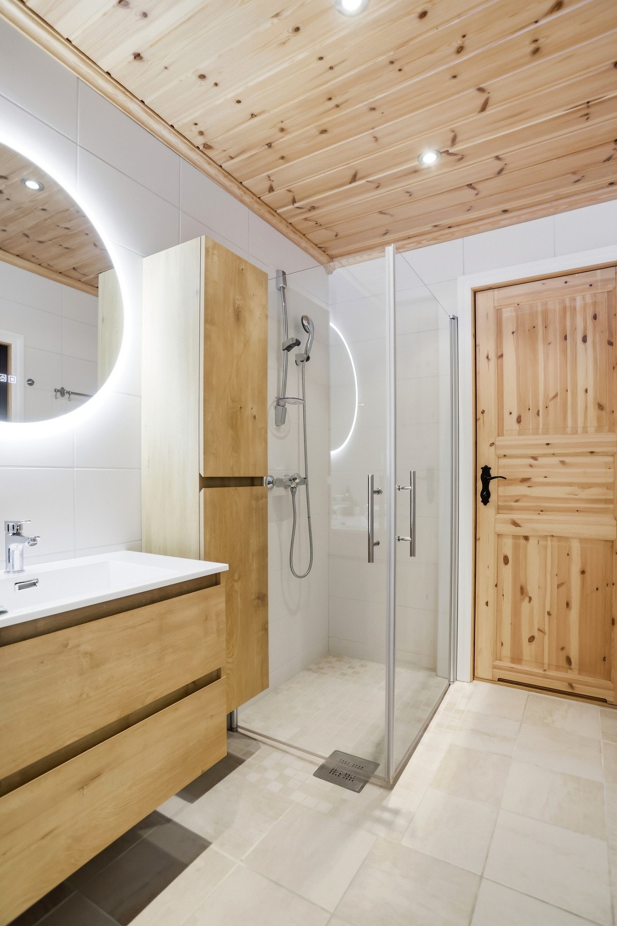 Baderommet har flislagte overflater og inneholder innredning med heldekkende servant, veggmontert toalett, dusjhjørne med glassdører, opplegg til vaskemaskin og tilkomst til badstue Galleribilde