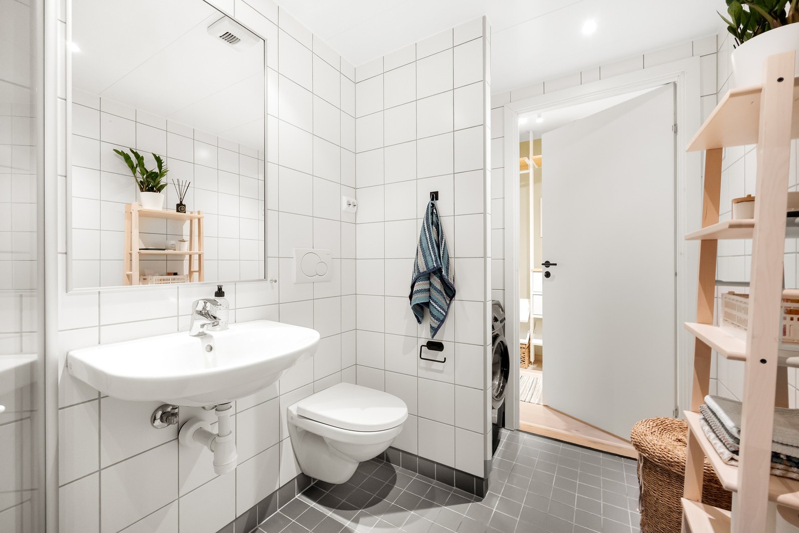 Badet er innredet med veggmontert servant med speil over, vegghengt toalett og dusjhjørne med svingdører og termostatstyrt blandebatteri, samt opplegg for vaskemaskin. Galleribilde