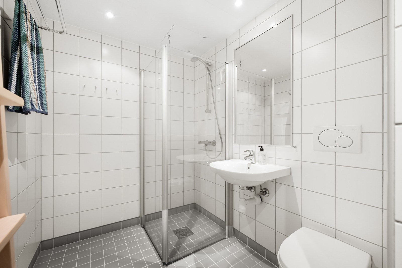 Rommet har flislagt gulv med gulvvarme, flislagte vegger og himling med downlights som gir et rent og tidløst uttrykk. Galleribilde