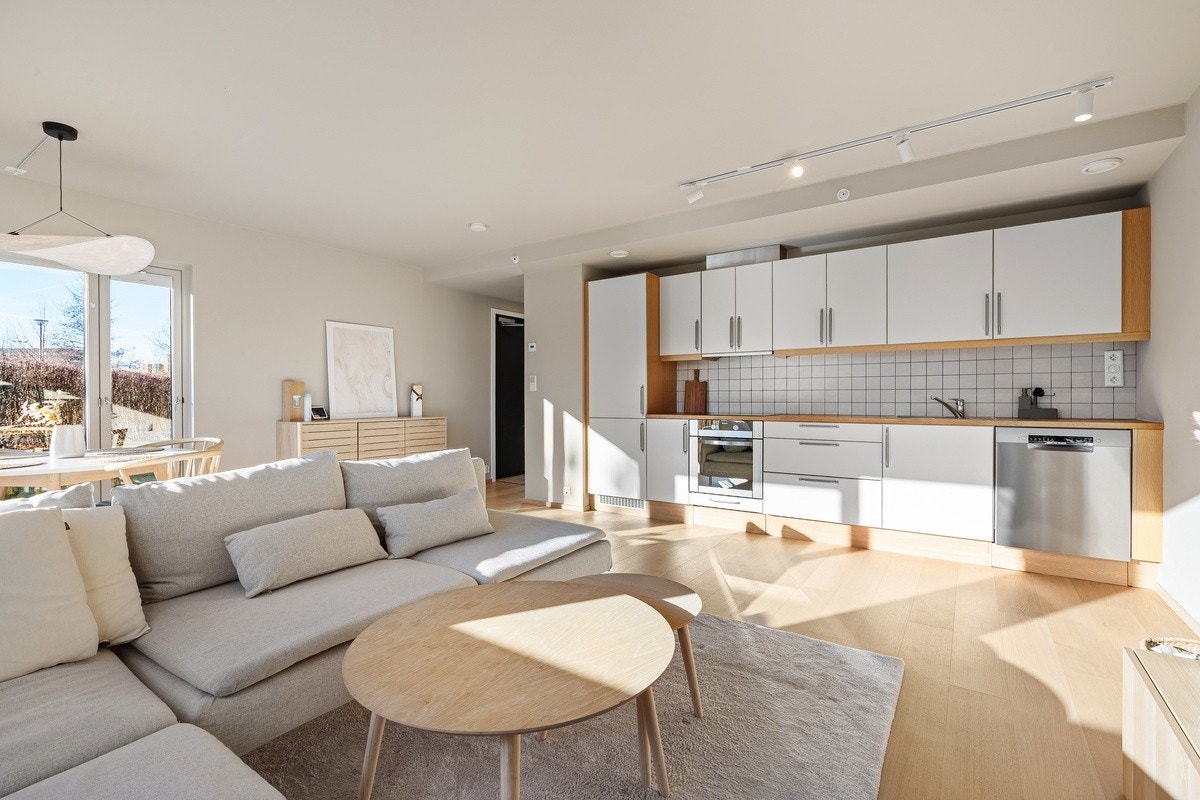 Stue og kjøkken i åpen løsning med store vindusflater som gir rikelig med naturlig lys og skaper en lys og innbydende atmosfære. Galleribilde