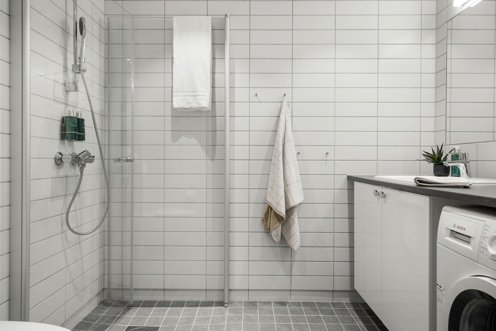 Stilrent bad, innredet med servantinnredning m/ vaskemaskin, vegghengt toalett, dusjhjørne. Flislagt gulv med varme Galleribilde