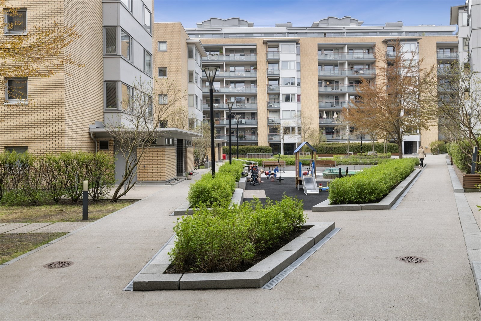 Fellesarealet med pent opparbeidede grøntområder, sitteplasser og lekeplass. Et hyggelig og barnevennlig uteområde mellom moderne boligblokker. Galleribilde