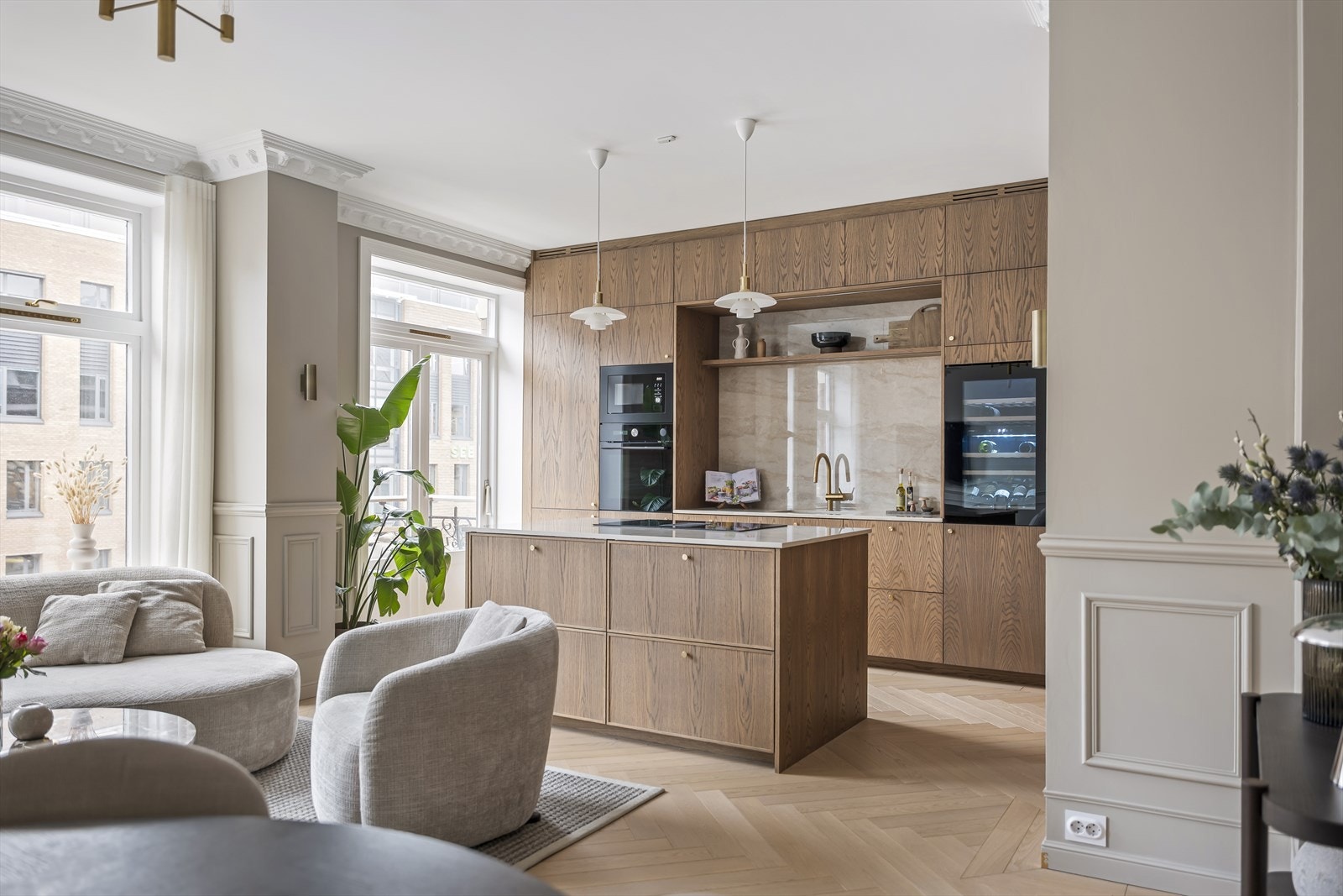 Kjøkkenøya fremstår som et elegant og funksjonelt midtpunkt i rommet, utført i samme varme materiale som resten av innredningen. Galleribilde