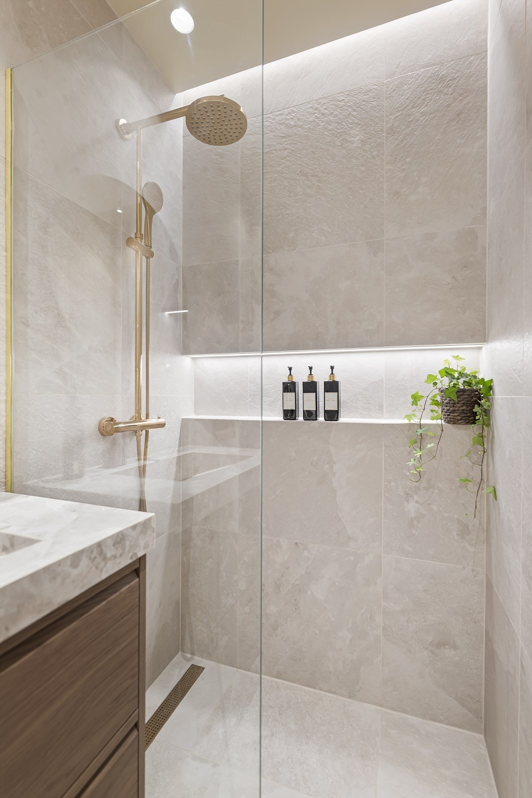 Dusjsonen har fast glassvegg og en praktisk, belyst nisje for oppbevaring. Galleribilde