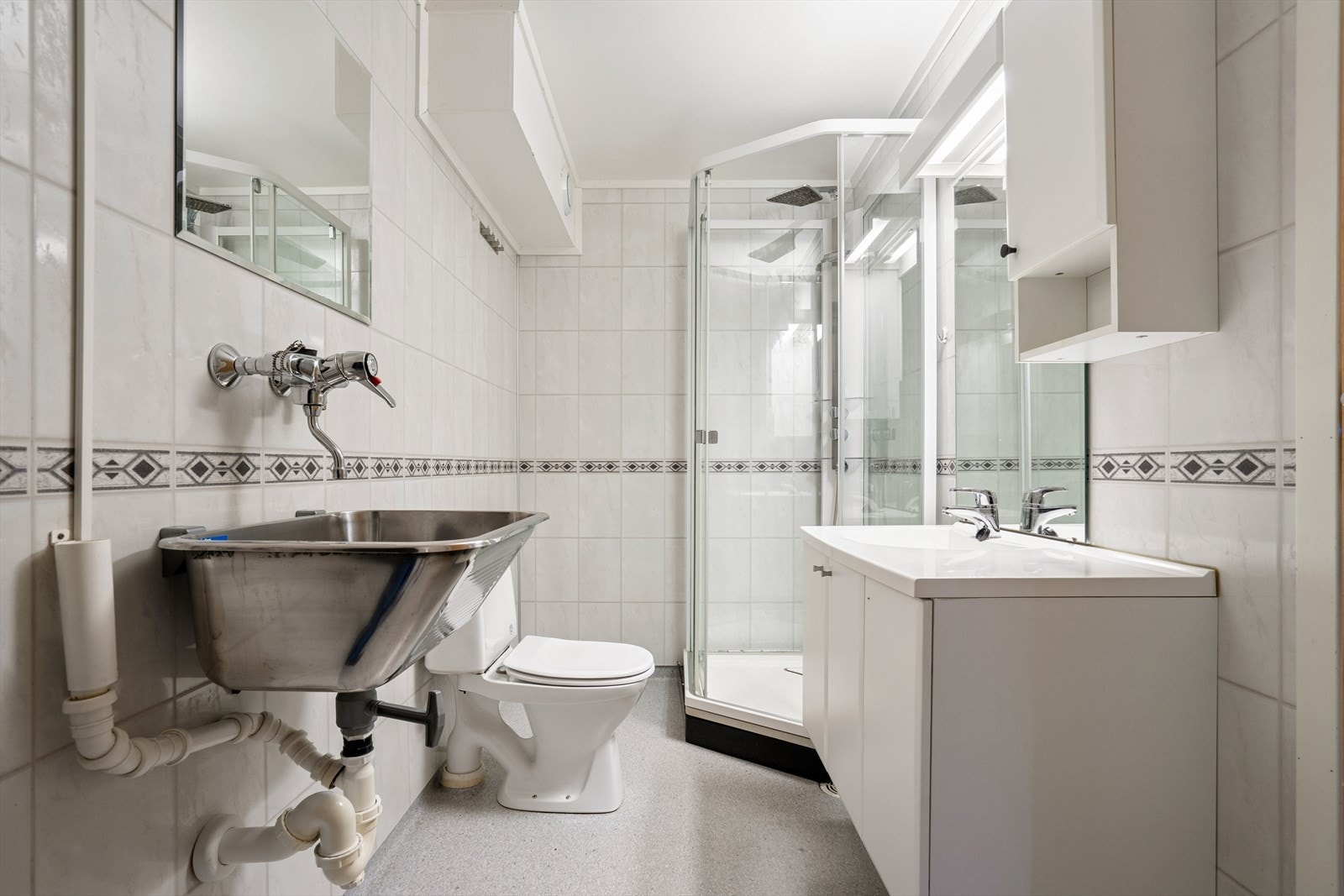 Badet er utstyrt med dusjkabinett, gulvstående toalett, og opplegg for vaskemaskin. Galleribilde