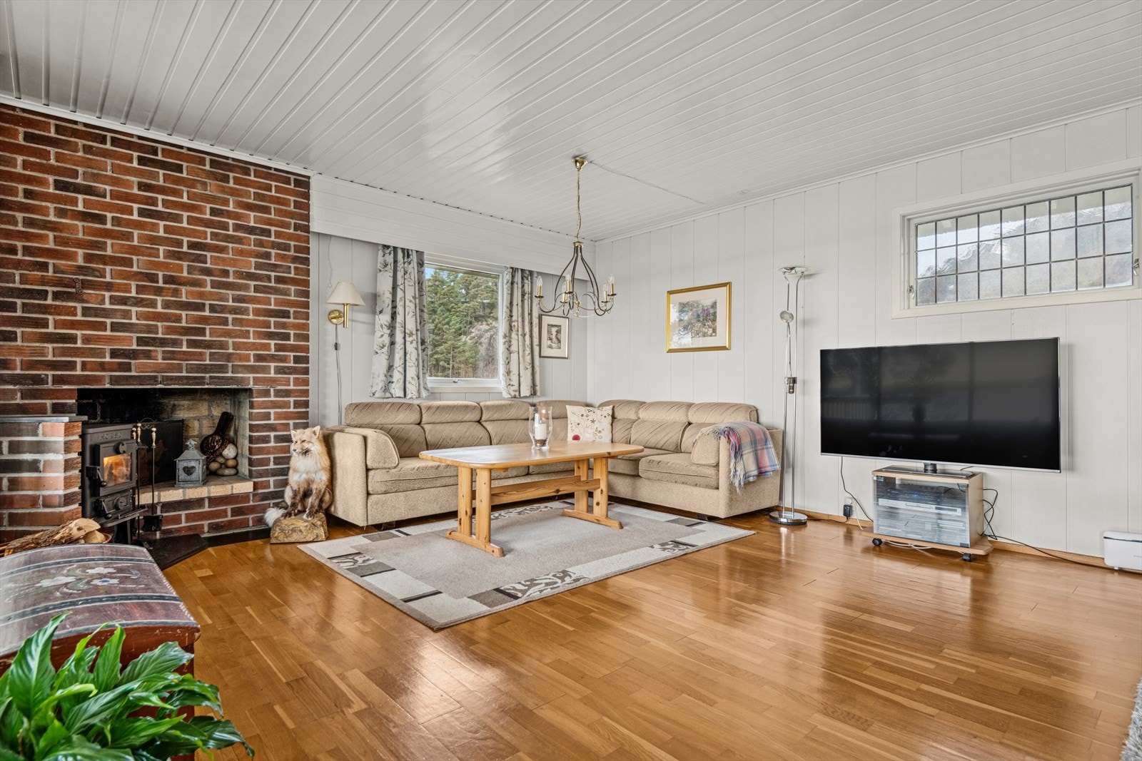 En lun og hyggelig sofakrok med både vedovn og åpen peis skaper en varm og stemningsfull atmosfære, perfekt for koselige kvelder året rundt. Galleribilde