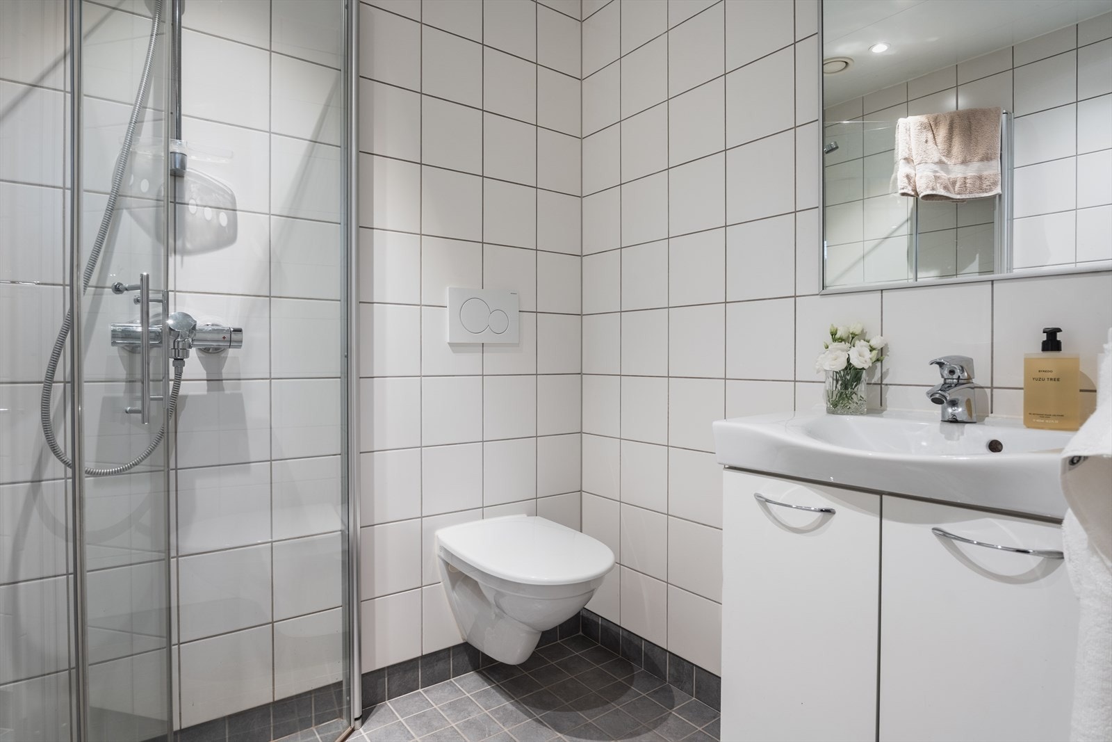 Helfliset bad med dusjhjørne med innfellbare dusjdører, nedfelt servant og vegghengt toalett i 1. etasje Galleribilde