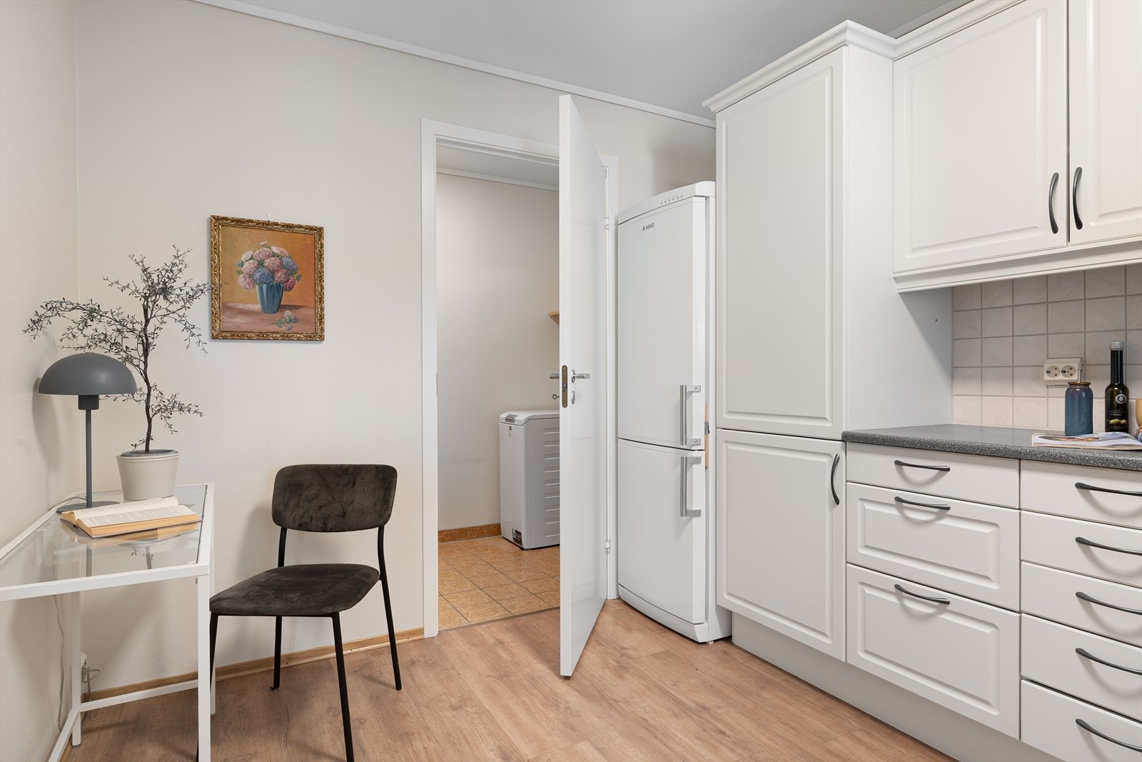 I tilknytning til kjøkkenet ligger et praktisk vaskerom med fliser på gulv, utslagsvask, opplegg til vaskemaskin og plass til ekstra kjøkkenutstyr. Galleribilde