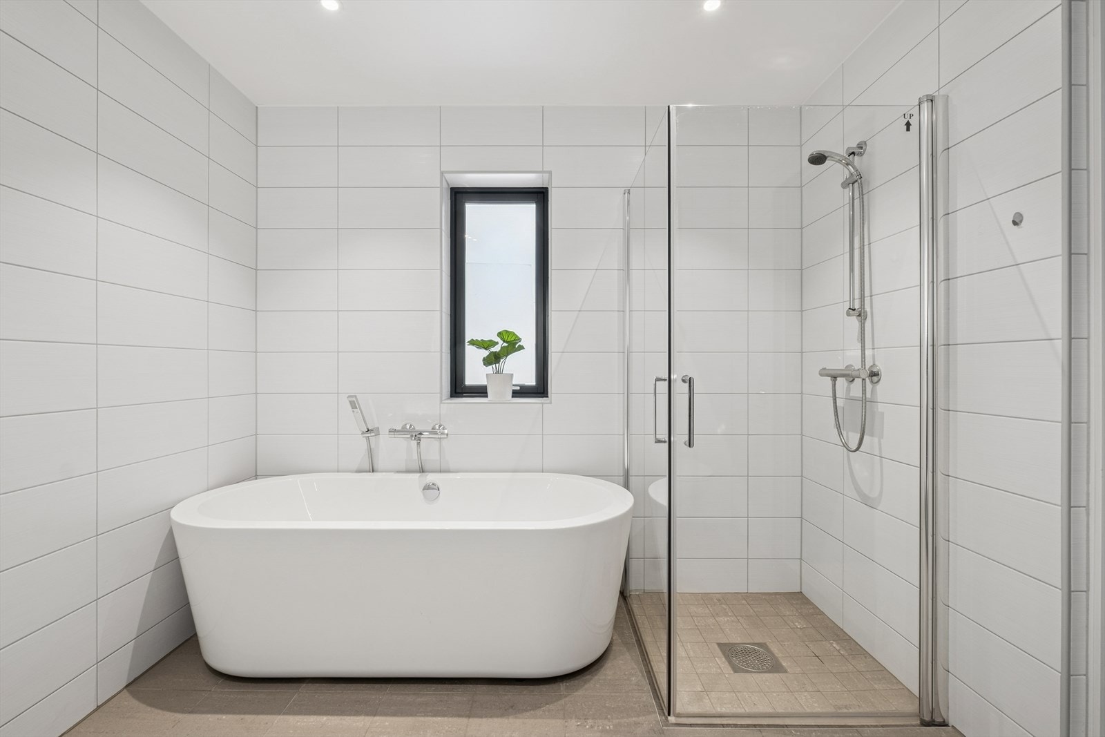 Badet er utstyrt med vegghengt toalett, dusjhjørne med glassvegger, badekar, samt baderomsinnredning med servant, blandebatteri og speil. Galleribilde