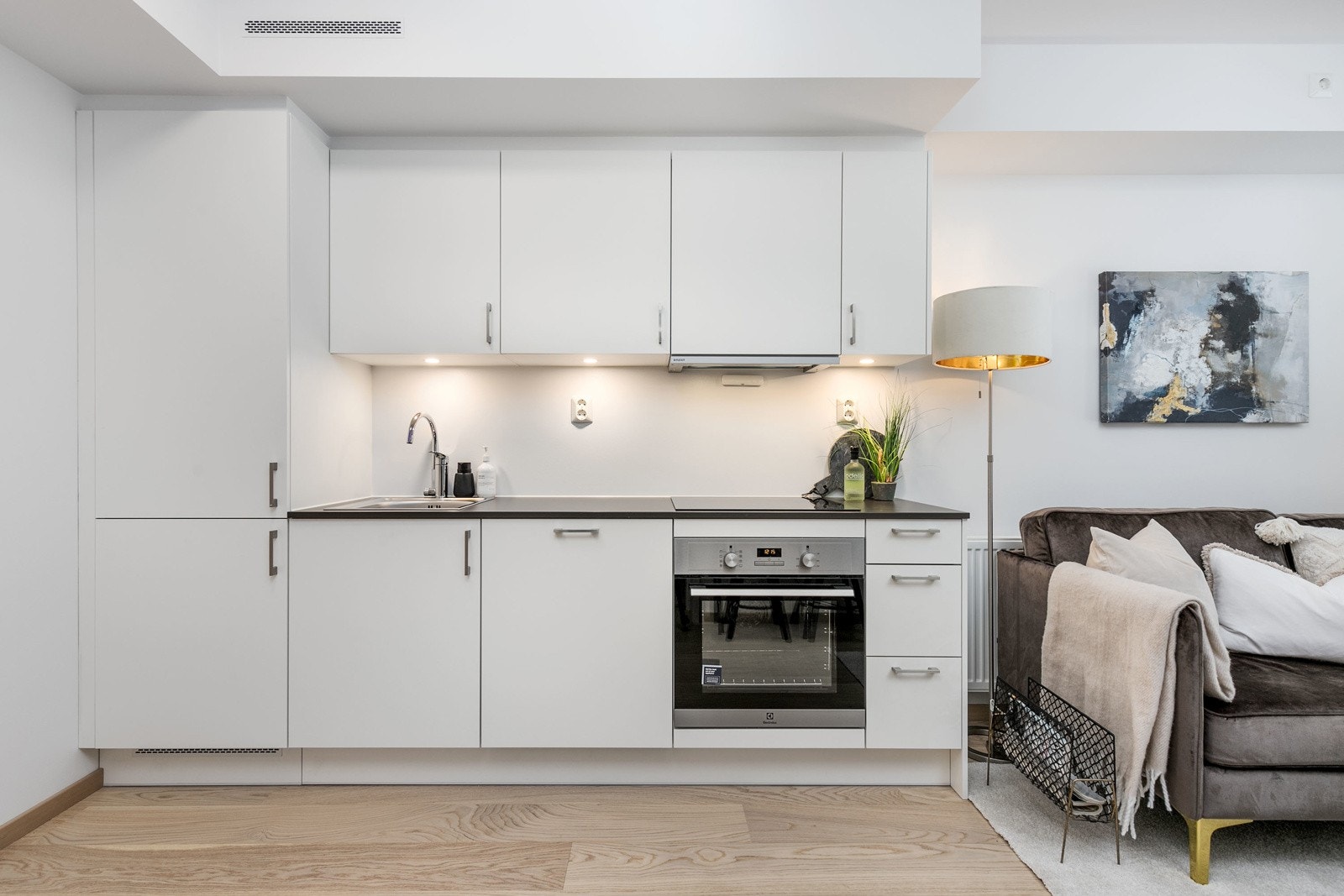 Kjøkkenet har integrert kjøl/frys, ovn, steketopp, oppvaskmaskin og uttrekkbar vifte. Belysning under skapinnredning. Bilde fra M103 Galleribilde