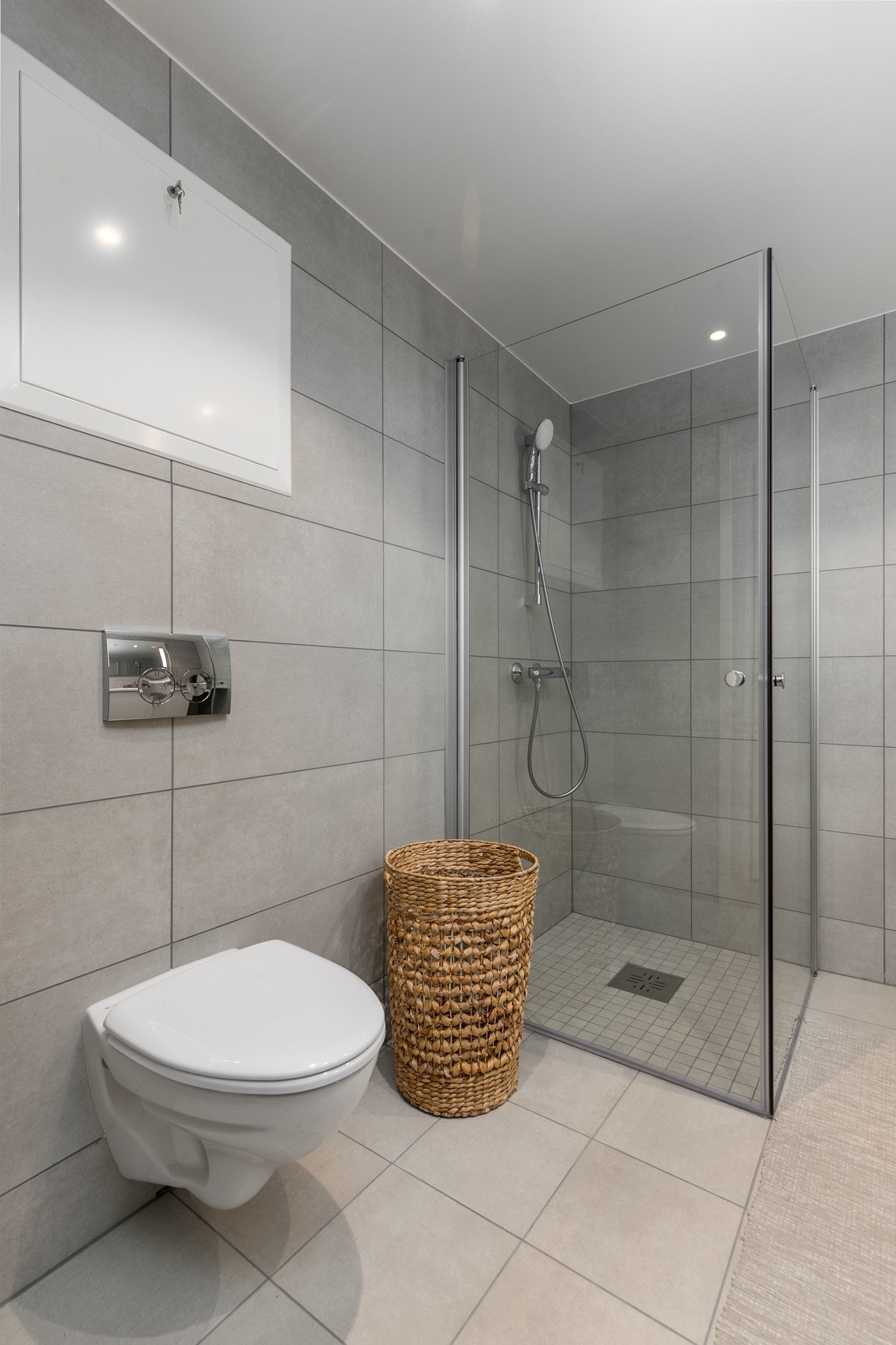 Badet har vegghengt toalett med innbygget sisterne, servant med skapinnredning samt speil med belysning. Bilde fra M103 Galleribilde