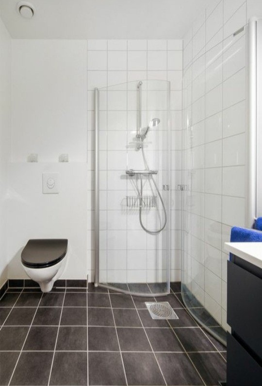 Baderom med romslig baderoms møblement, vegghengt toalett og praktisk dusj med vendbare glassvegger. Galleribilde