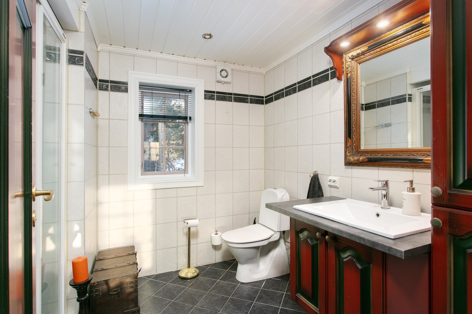 Romslig bad med flislagt gulv med gulvvame, flislagte vegger, baderomsinnredning, wc og dusjhjørne Galleribilde