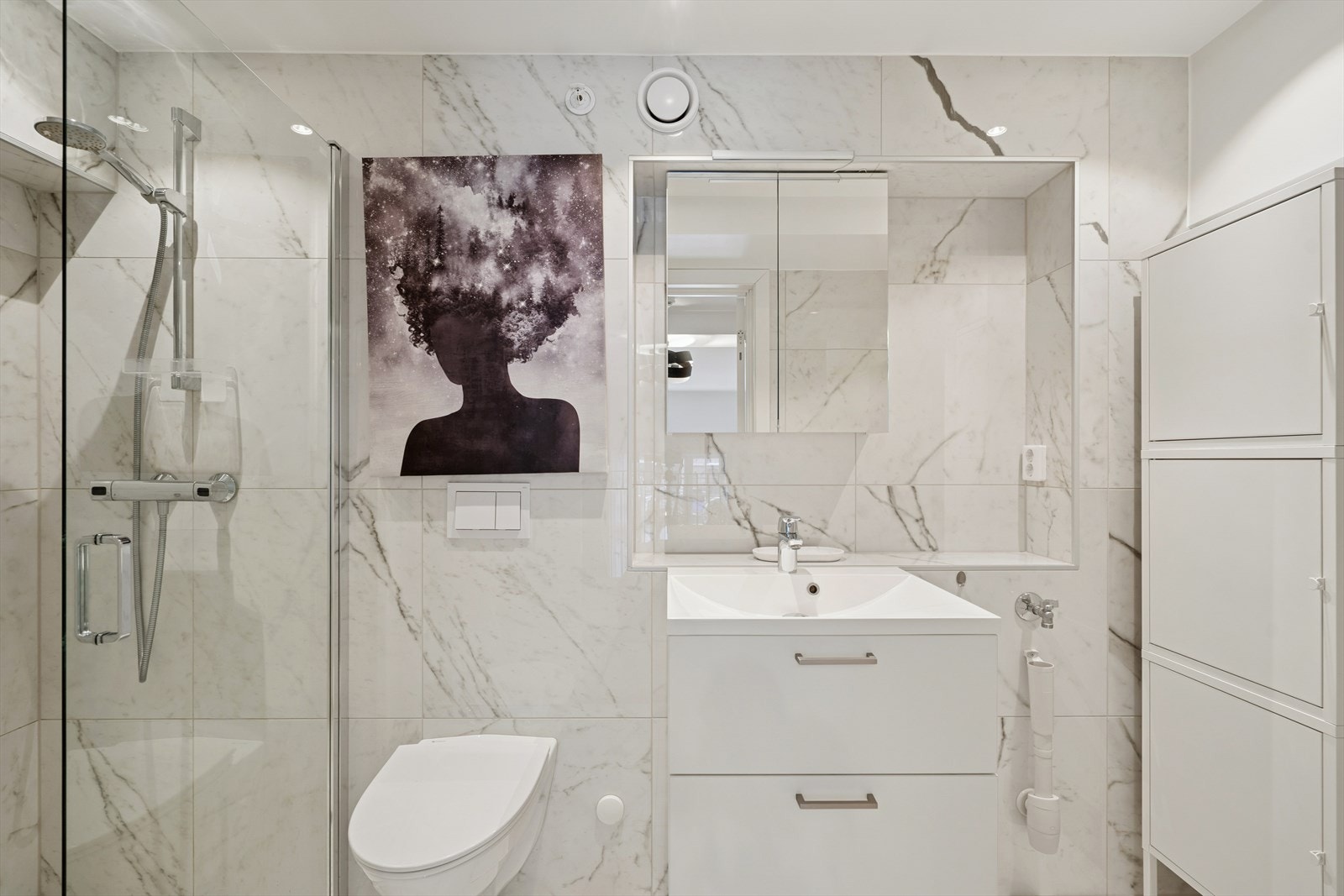 Rommet er innredet med pen servantinnredning med skuffer med profilerte fronter, vegghengt toalett og dusjhjørne. Galleribilde