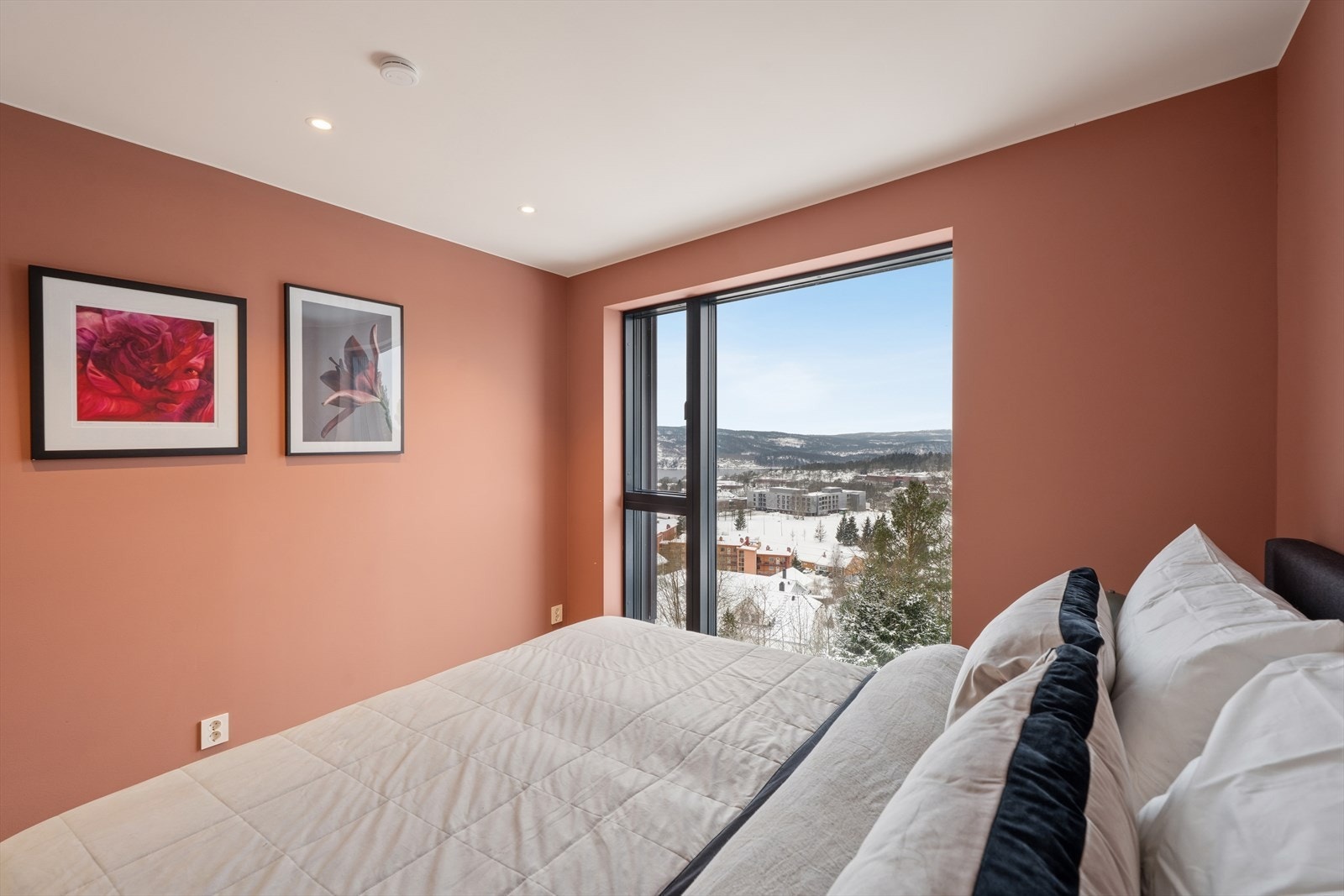 Hovedsoverommet utmerker seg med store vindusflater som gir rikelig naturlig lys, downlights i himlingen og en dus, rødbrun veggfarge som skaper en varm og elegant atmosfære Galleribilde