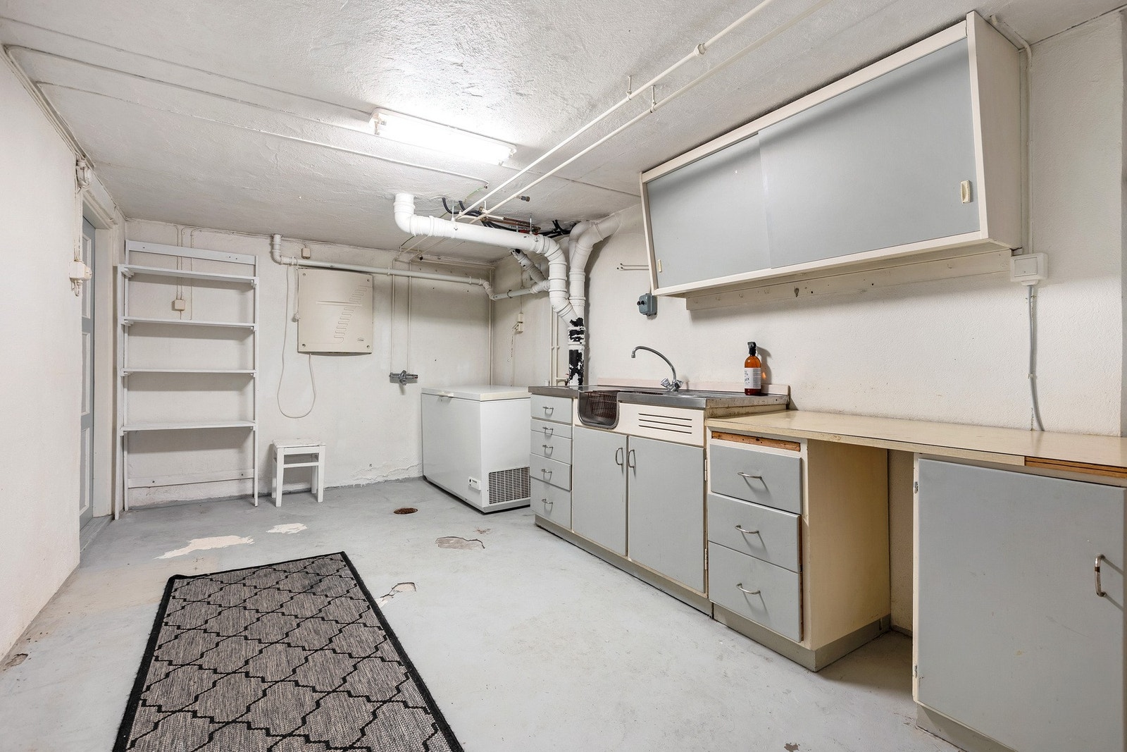 Et av rommene i kjelleren med flere bruksmuligheter har malte muroverflater og gode arbeidsflater og praktiske løsninger med en eldre innredning med vask og oppbevaringsskap. Galleribilde