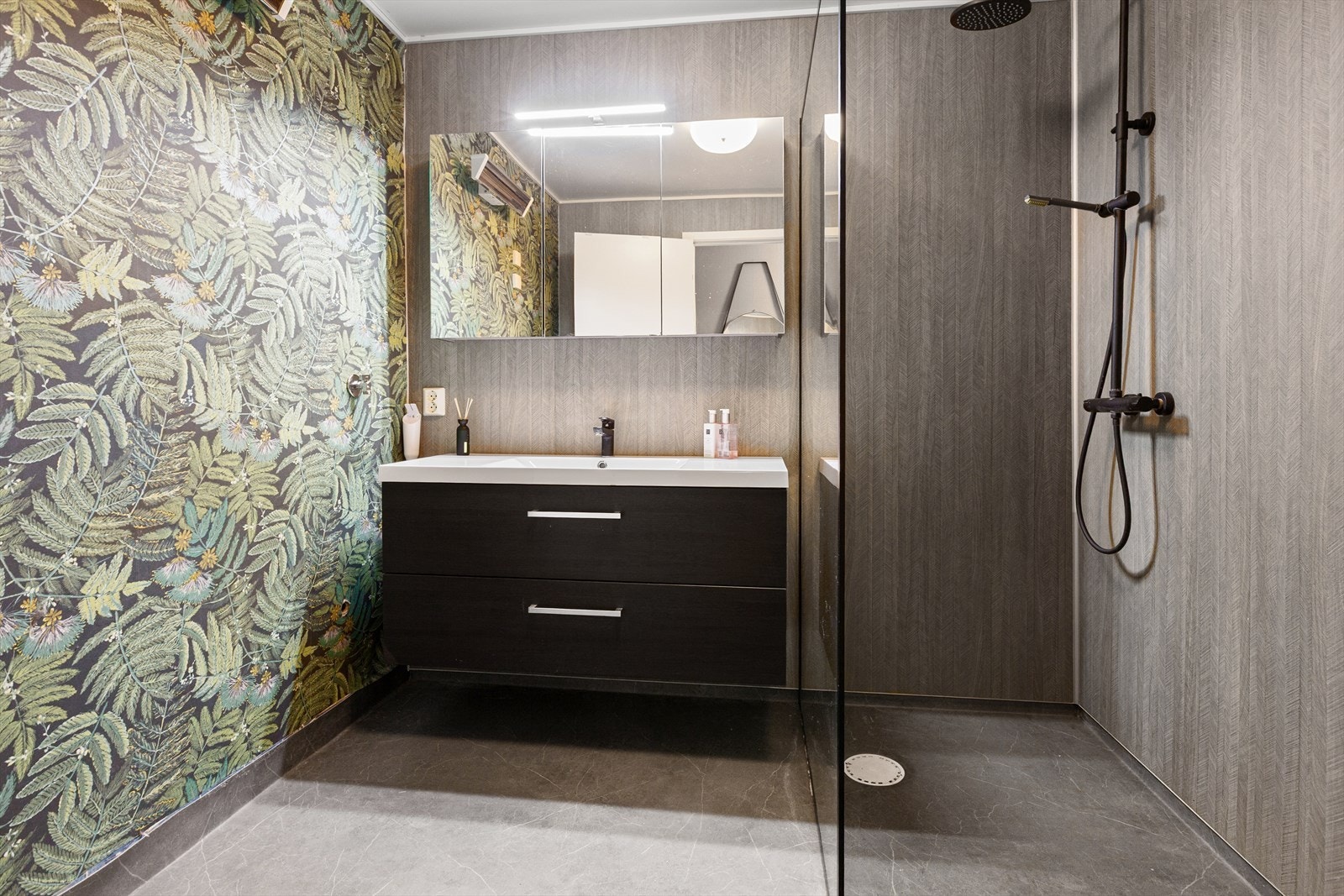 Baderom som er innredet med dusj, vegghengt toalett og opplegg for vaskemaskin. Galleribilde