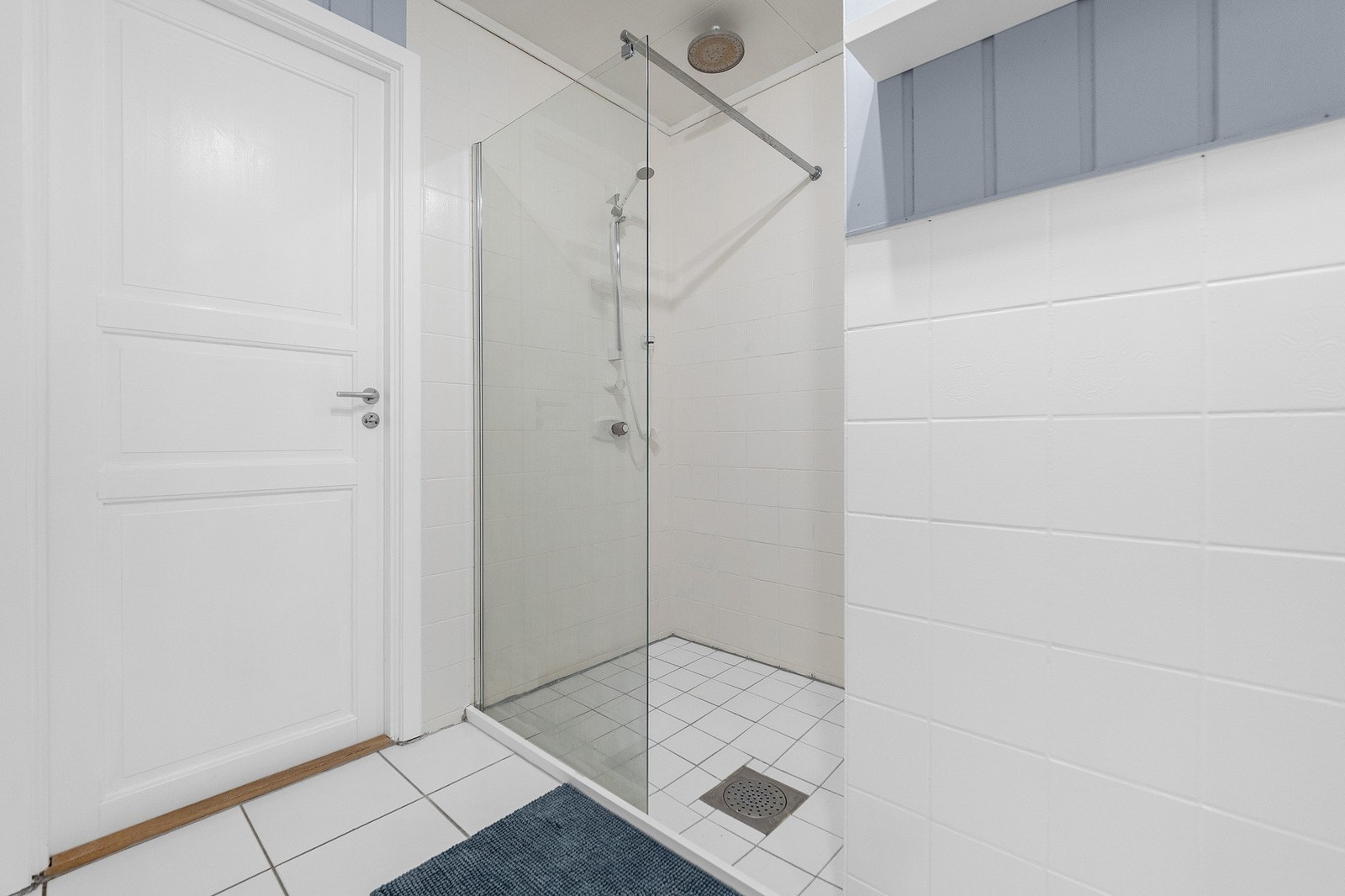 Badet har dusjkabinett med glassvegg og hvite fliser på både vegger og gulv. Galleribilde