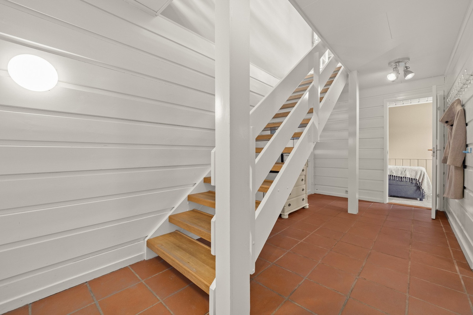 Lyst inngangsparti med tretrapp og flislagt gulv, som gir tilgang til andre rom. Galleribilde