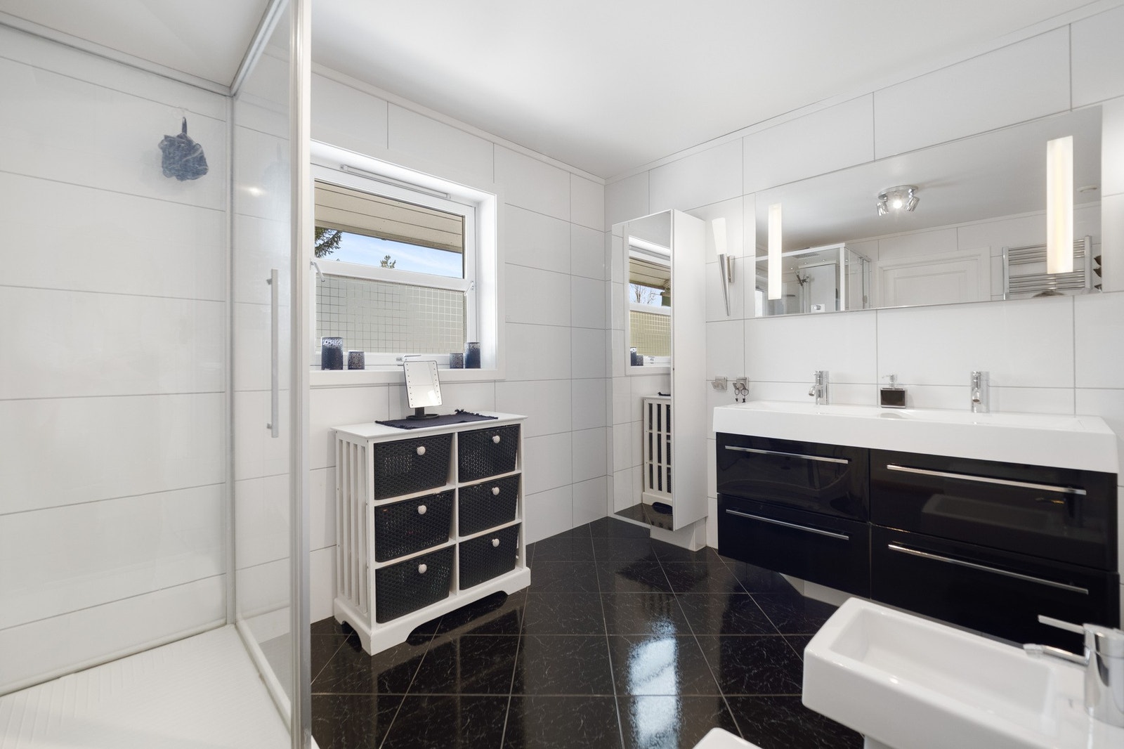 Badet har dusj med glassdør, stor servant med to kraner, og vindu som gir naturlig lys. Galleribilde