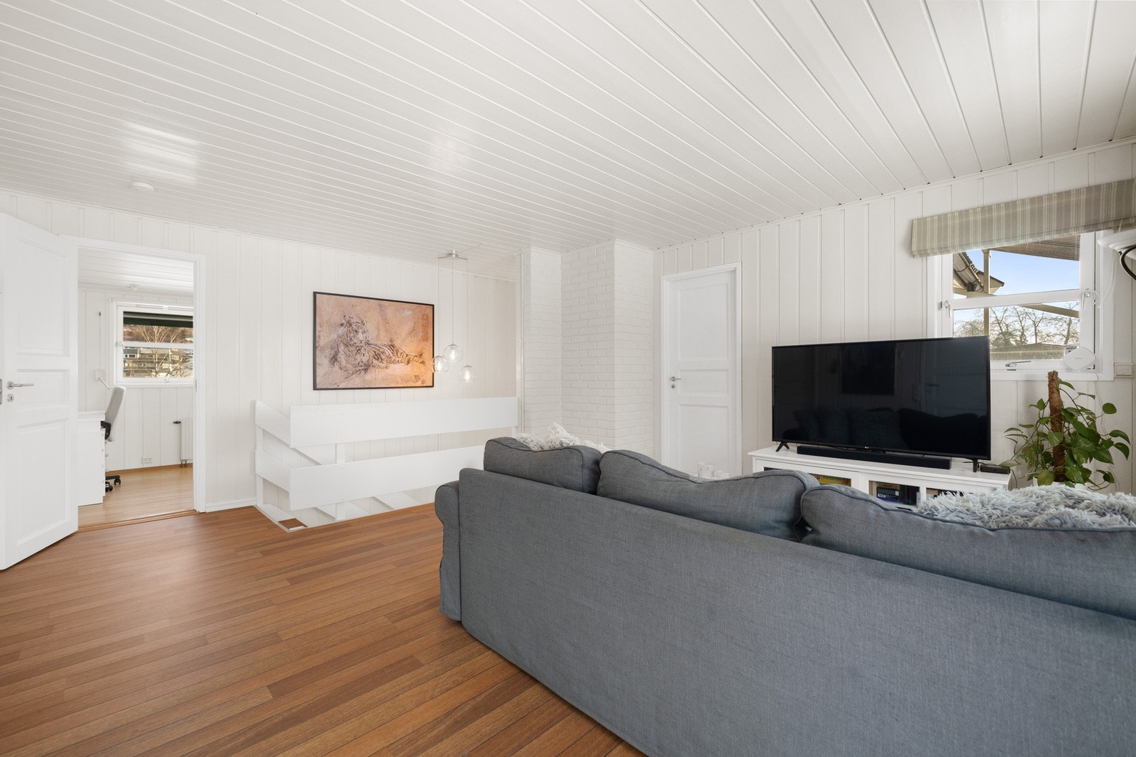 Stue med lyse vegger og tak, med skips-inspirert gulv. Galleribilde