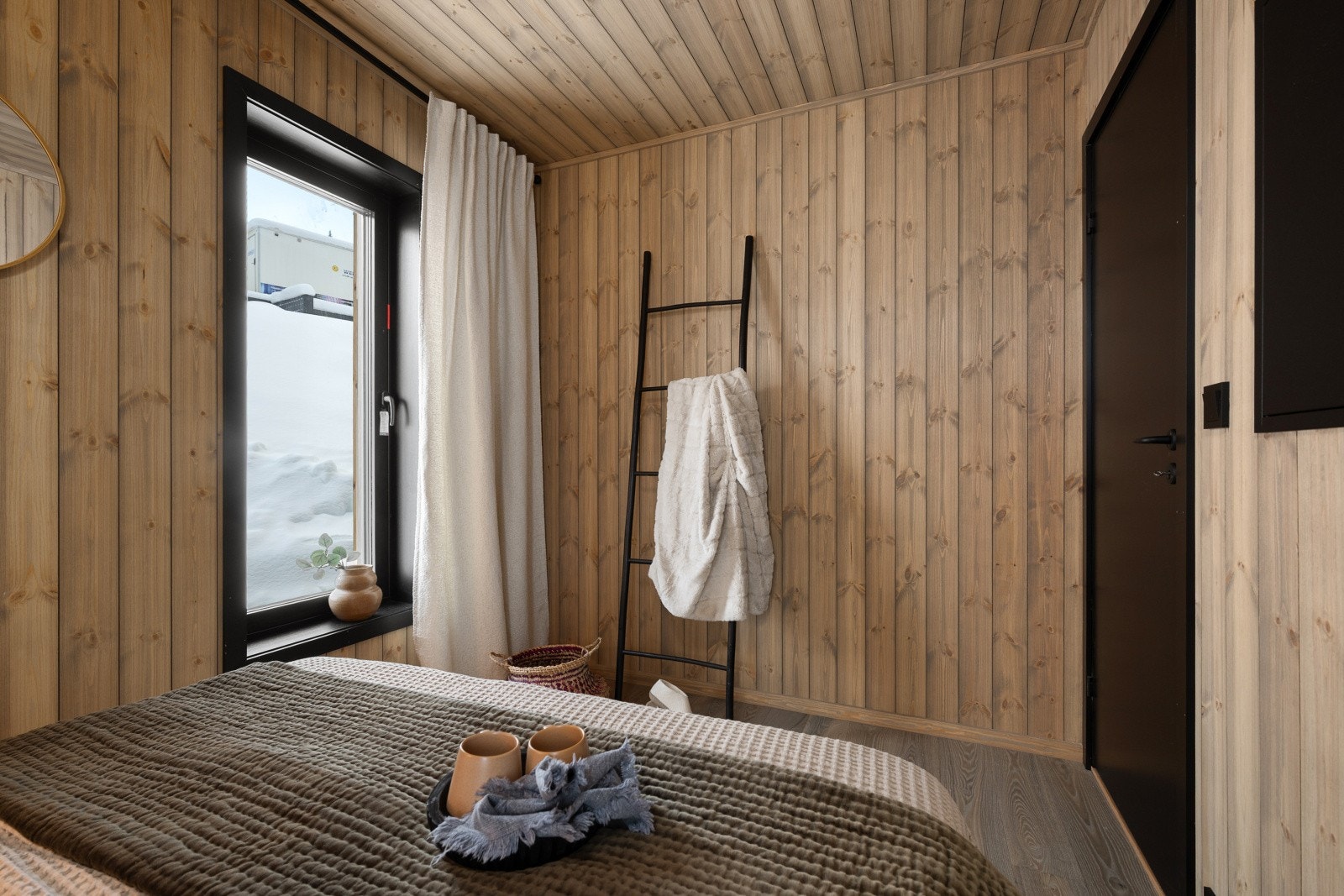 Store vinduer gir rikelig med naturlig lys i rommet, som fremhever de varme trepanelene. Galleribilde