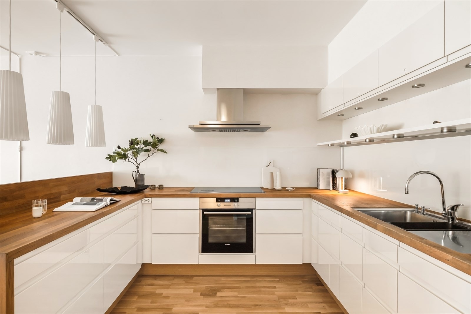 Flott og tidløst kjøkken med rikelig skap- og benkeplass. Kjøkkeninnredning i lyse, glatte fronter kombinert med heltre benkeplate gir et rent og moderne uttrykk. Galleribilde