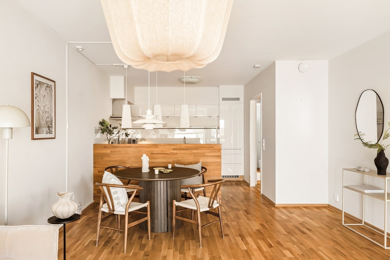 Lys og stilren stue med åpen kjøkkenløsning. Store flater, varme tregulv og gjennomtenkte materialvalg skaper en rolig og harmonisk atmosfære med god plass til både hverdagsliv og sosiale sammenkomster. Galleribilde