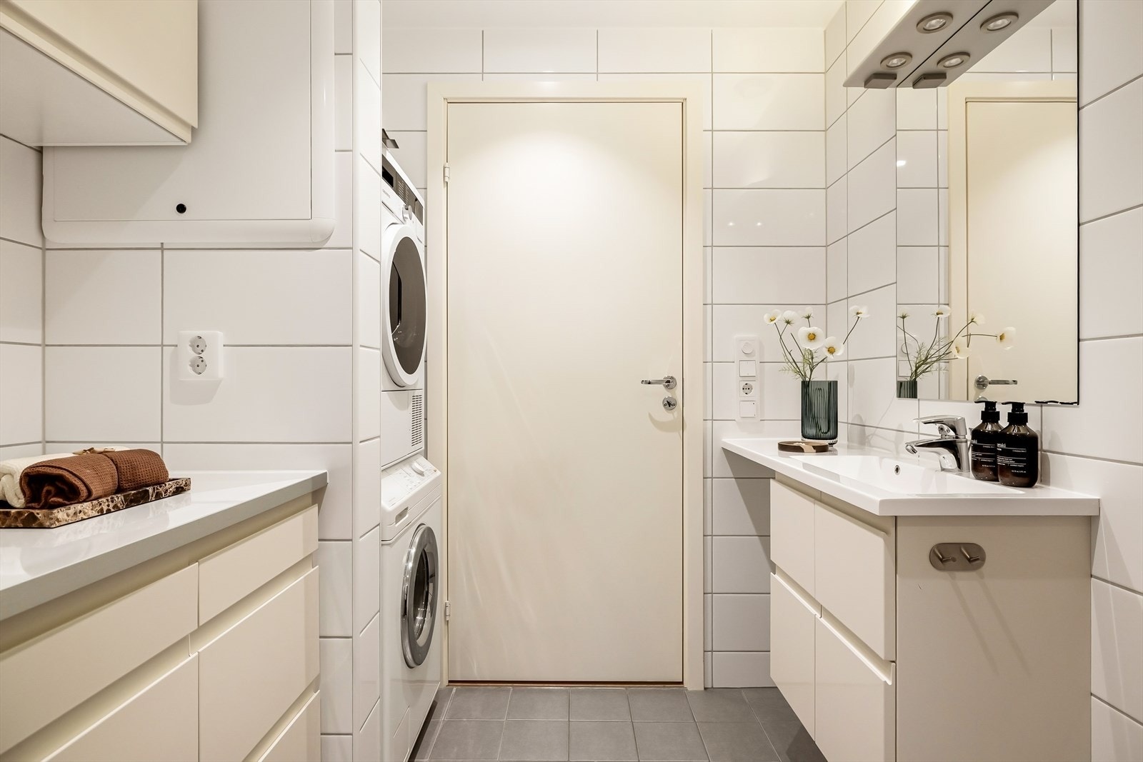 Delikat og funksjonelt bad plassert i gangen, praktisk tilgjengelig for gjester. Badet har lyse fliser, rolige fargetoner og innredning med god oppbevaringsplass, samt opplegg for vaskemaskin som gir en effektiv og hverdagsvennlig løsning. Galleribilde