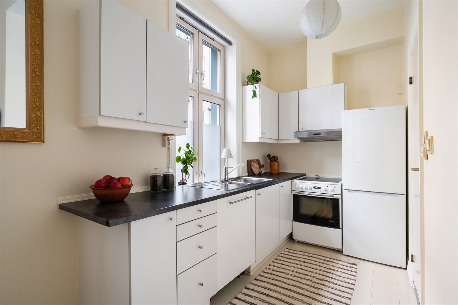 Kjøkkenet har en hvit innredning med glatte fronter og en slitesterk laminert benkeplate. Her får du plass til frittstående og integrerte hvitevarer. Galleribilde