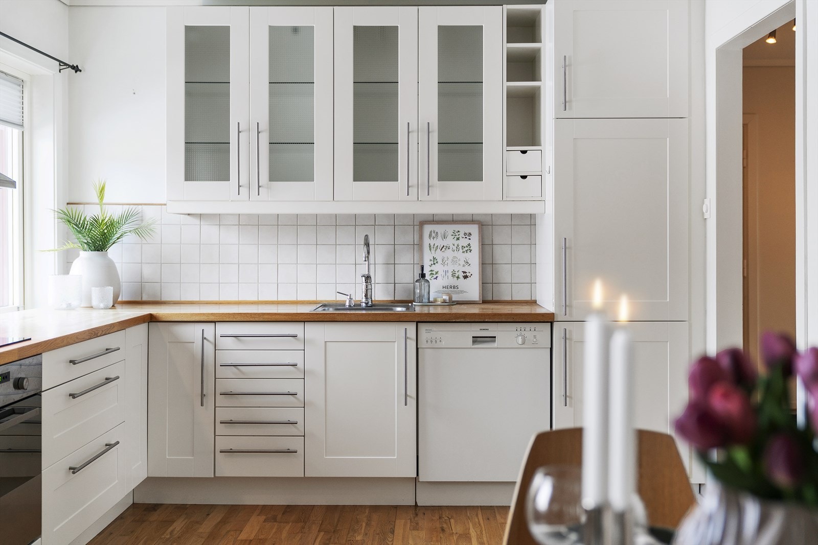 Kjøkkeninnredningen har hvite, profilerte fronter og heltre benkeplate Galleribilde