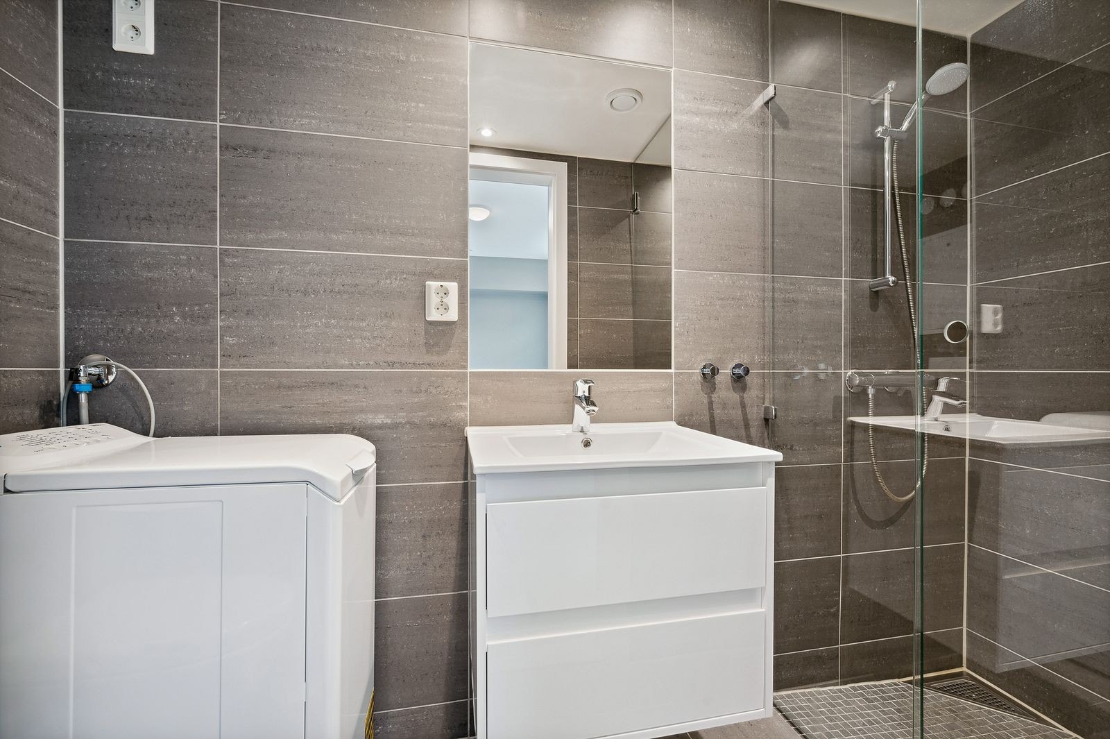 Moderne flislagt bad, badet er utstyrt med vaskemaskin. Galleribilde