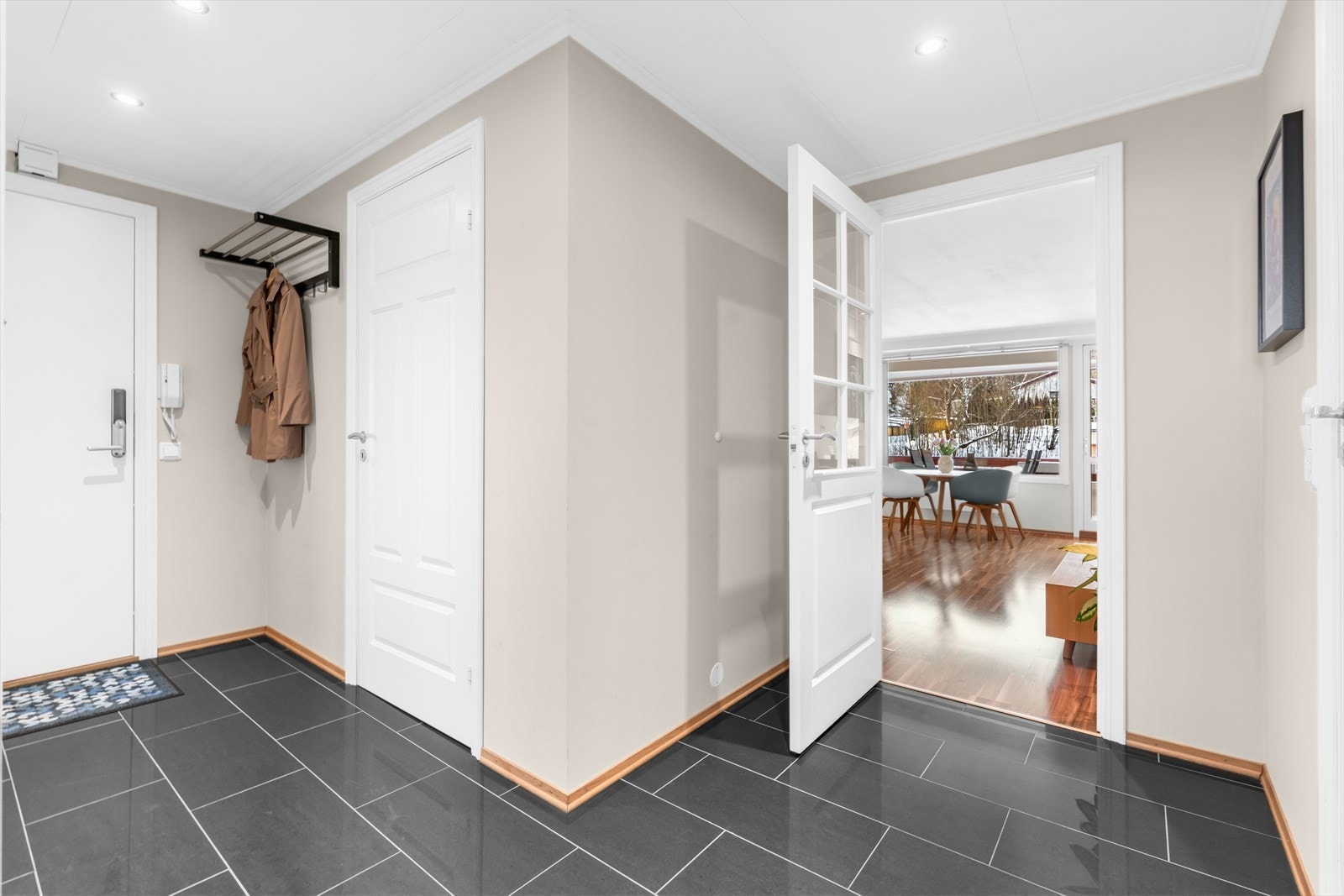 Fra den flislagte entréen leder en dør med glass og sprosser inn til stuen. Galleribilde