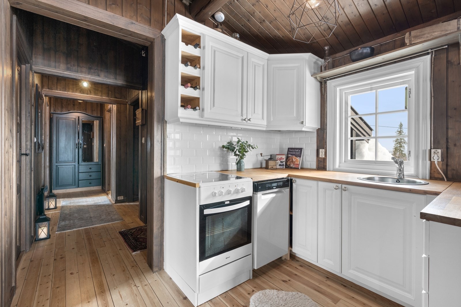 Kjøkken med oppvaskmaskin, komfyr og nedfelt servant. Fliser under overskap og heltre benkeplate. Galleribilde