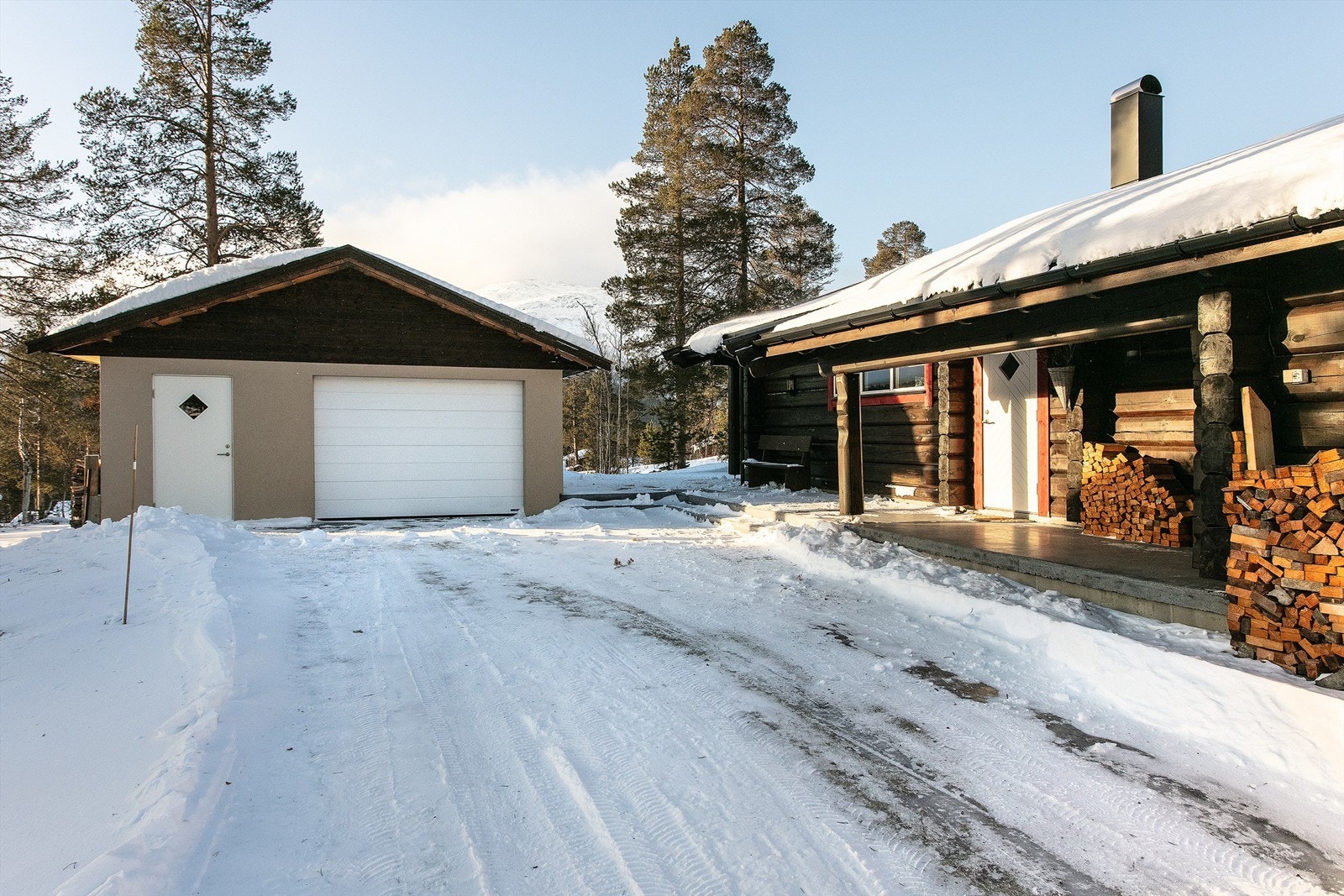 Gårdsplass med garasje og fasade/inngangsparti til hytten Galleribilde