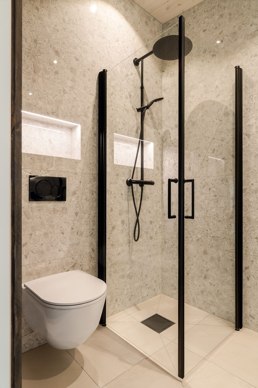 Badet er rålekkert med flislagt gulv/vegger og nisjer for oppbevaring. Galleribilde