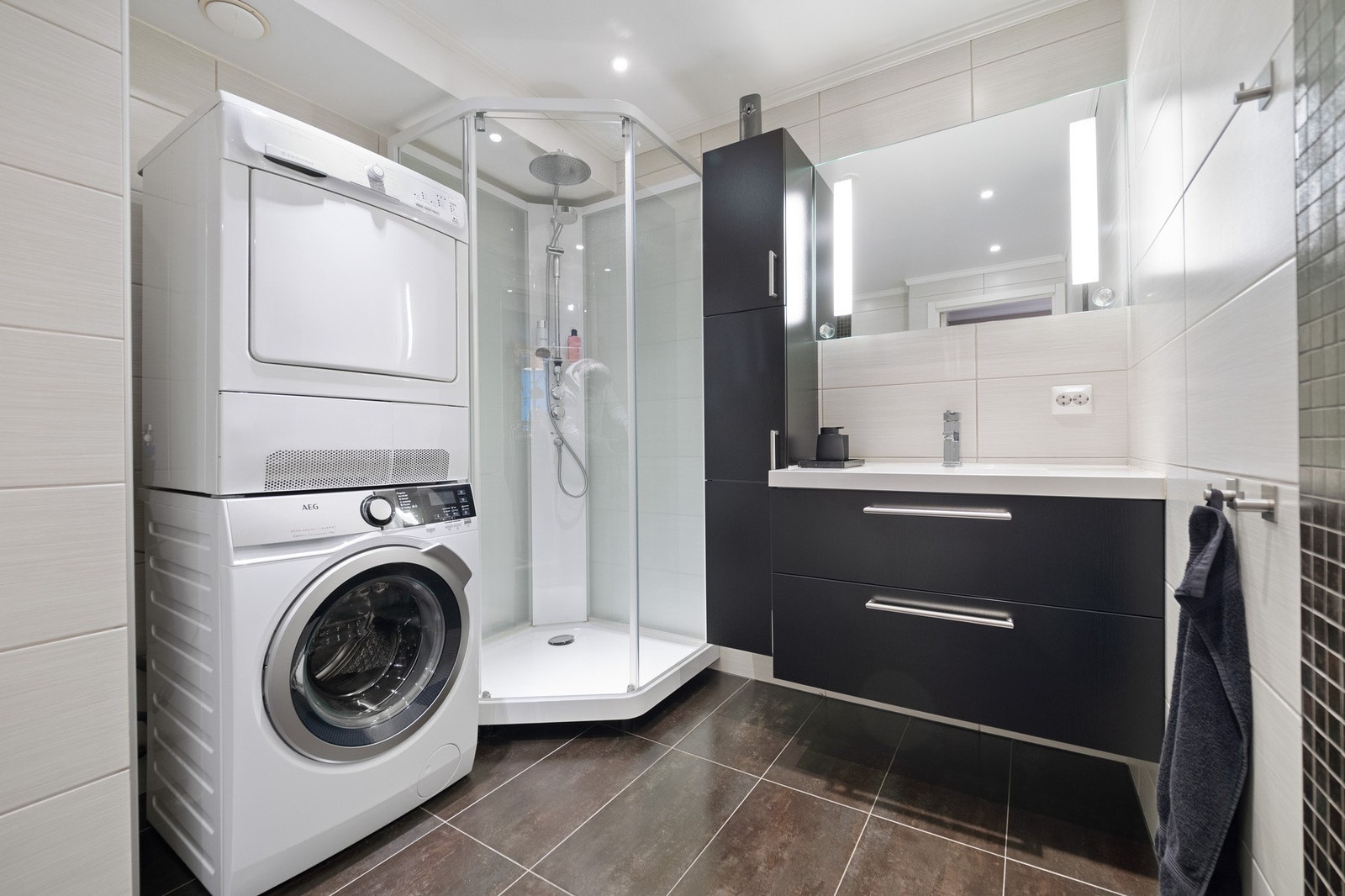 Badet har dusjkabinett, vaskemaskin med tørketrommel, og moderne baderomsinnredning med speil og god belysning. Galleribilde