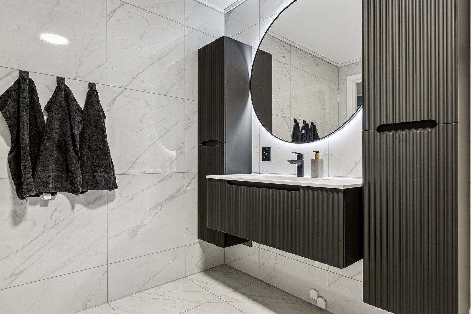 Baderommet er utstyrt med flislagt gulv med varme, dusjhjørne med dører. vegghengt toalett og opplegg for vaskemaskin. Galleribilde