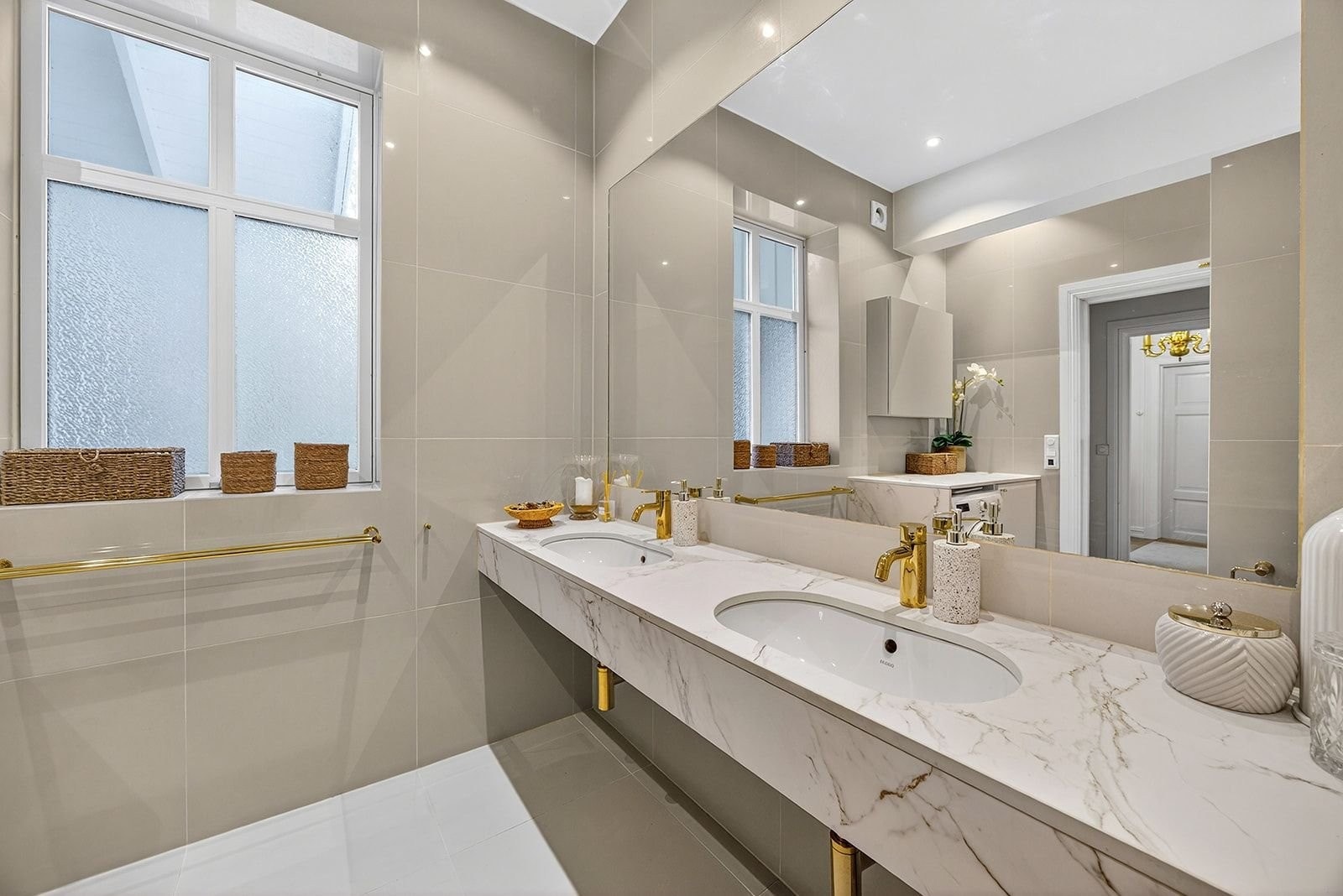 Dobbelt servant og lettstelt benkeplate marmormønstret høytrykksporselen. Stort speil og downlights. Galleribilde