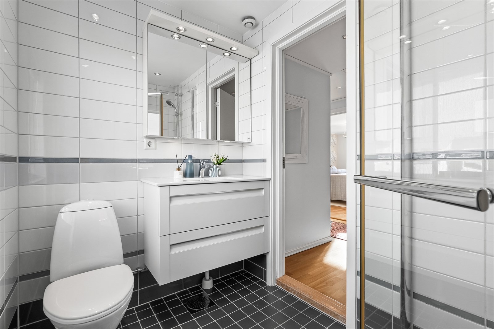 Pent flislagt bad med varmekabler. Badet er innredet med skap med glatte fronter, overskap med speilfront, servant og klosett. Galleribilde