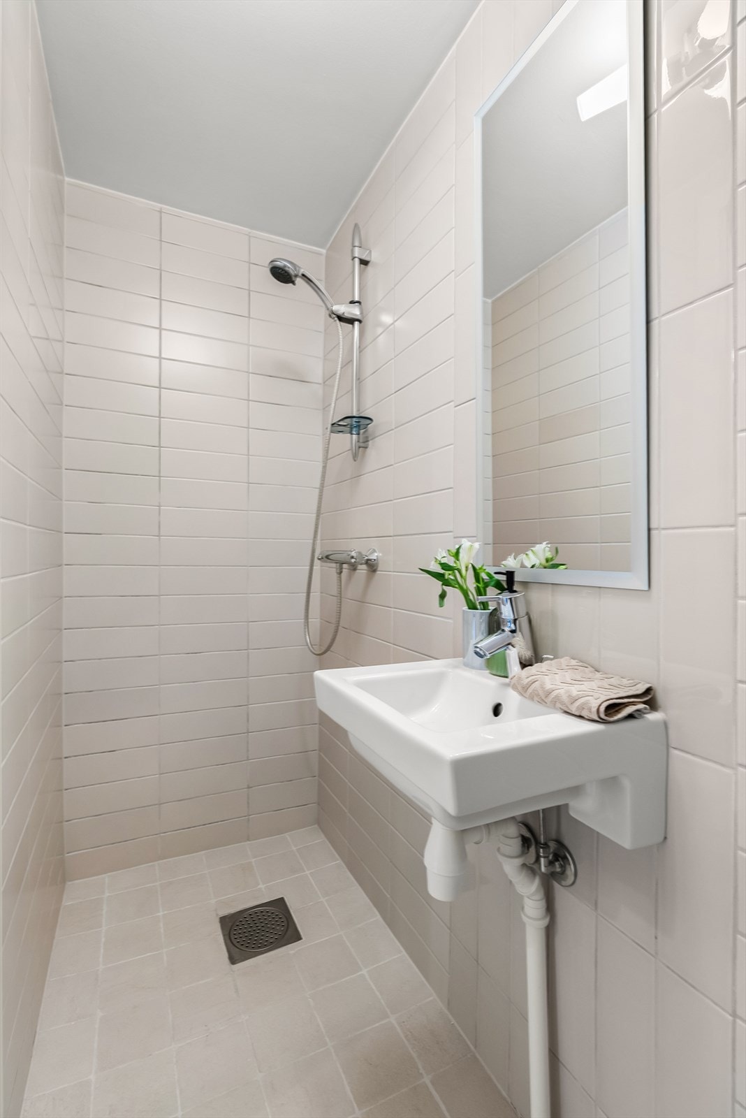 Flislagt bad med varmekabler i kjeller. Badet har servant og dusj på gulv. Galleribilde