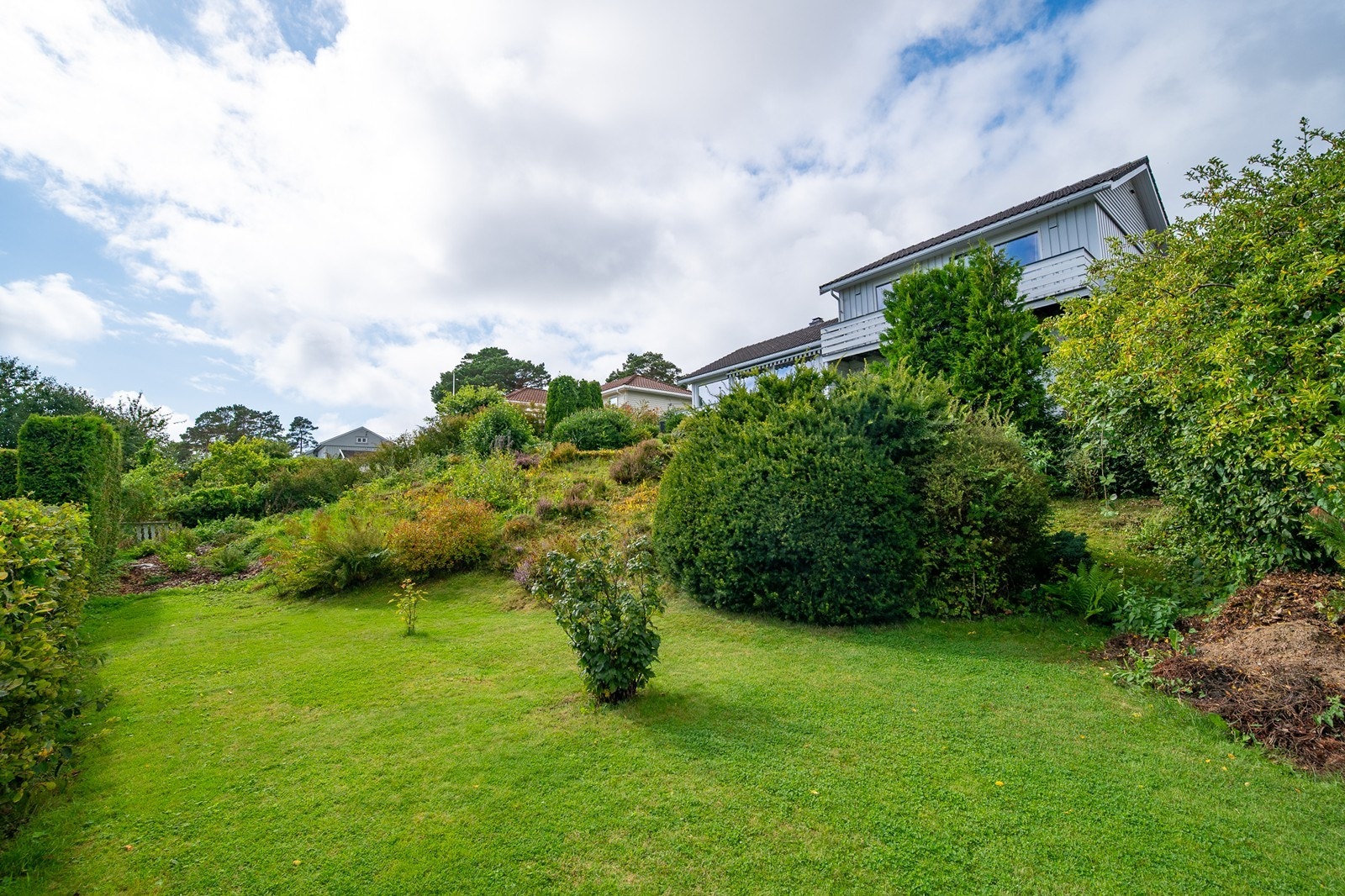 Romslig tomt med stor hage. Her på det nederste planet er det god plass til trampoline, huskestativ, frukttær, drivhus eller lignende. Galleribilde