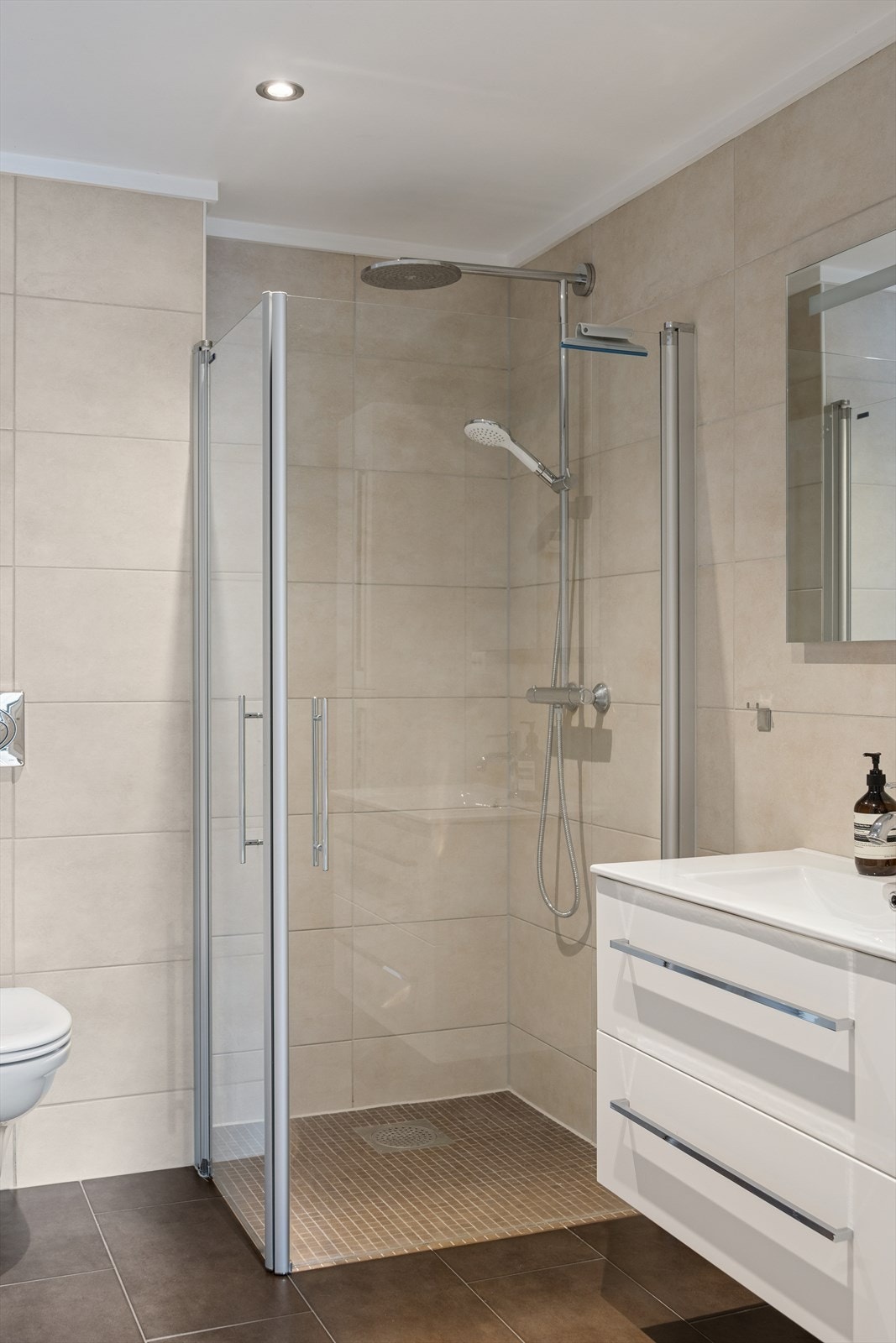 Badet er innredet med praktisk baderomsinnredning, speil og skapplass som gir god lagringskapasitet. Sanitærutstyret består blant annet av et vegghengt toalett, som både gir et moderne uttrykk og gjør renhold enklere. Galleribilde