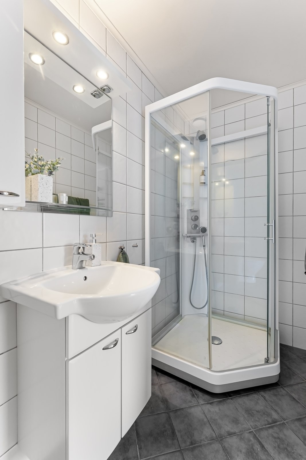 Flislagt bad i 1. etasje med innredning bestående av nedfelt servant, veggskap, speil, toalett og dusjkabinett. Galleribilde