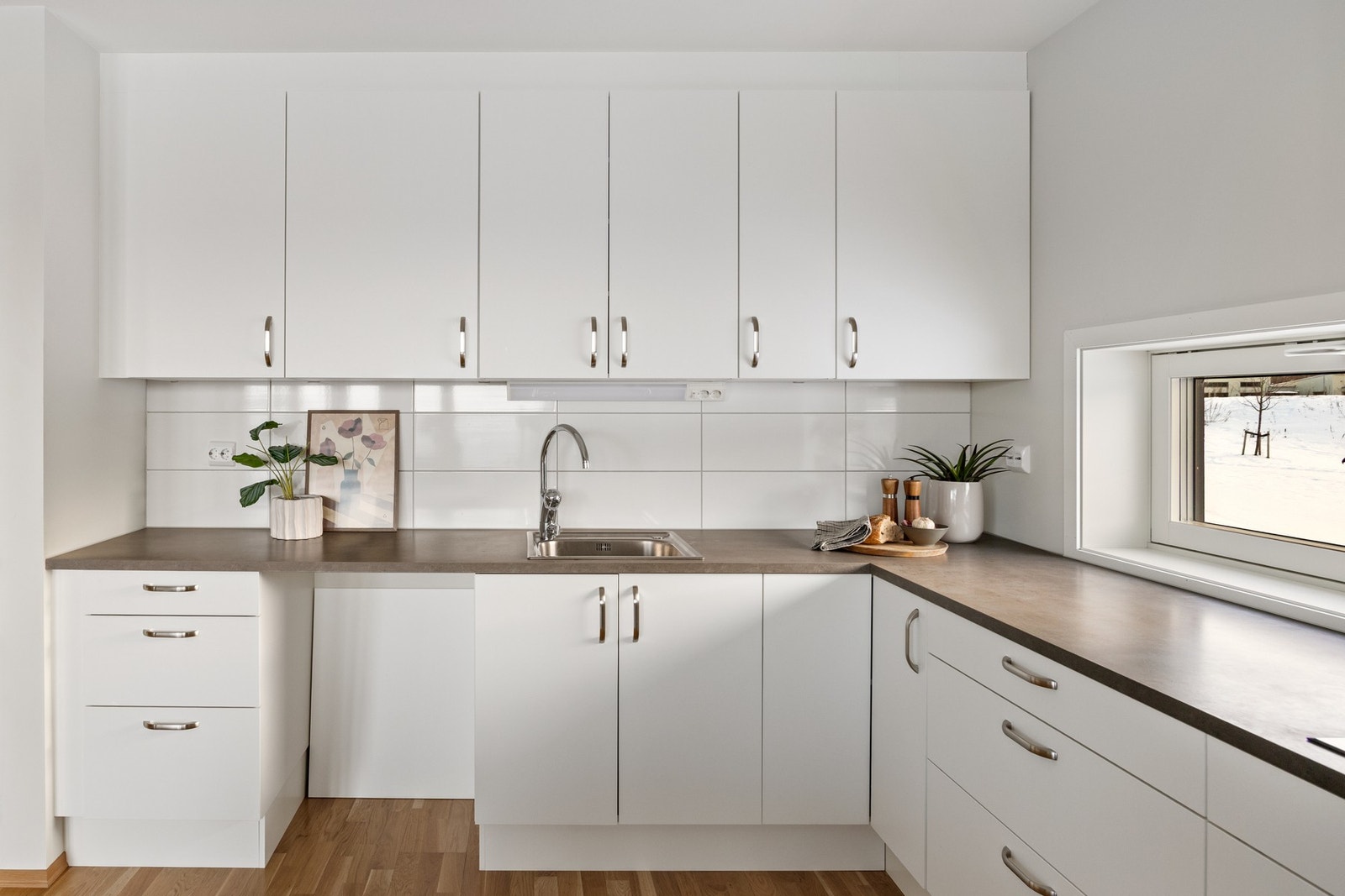 Det er godt med benk- og oppbevaringsplass. Endebeliggenheten sørger for at leiligheten har vindu over kjøkkenbenken også. Galleribilde