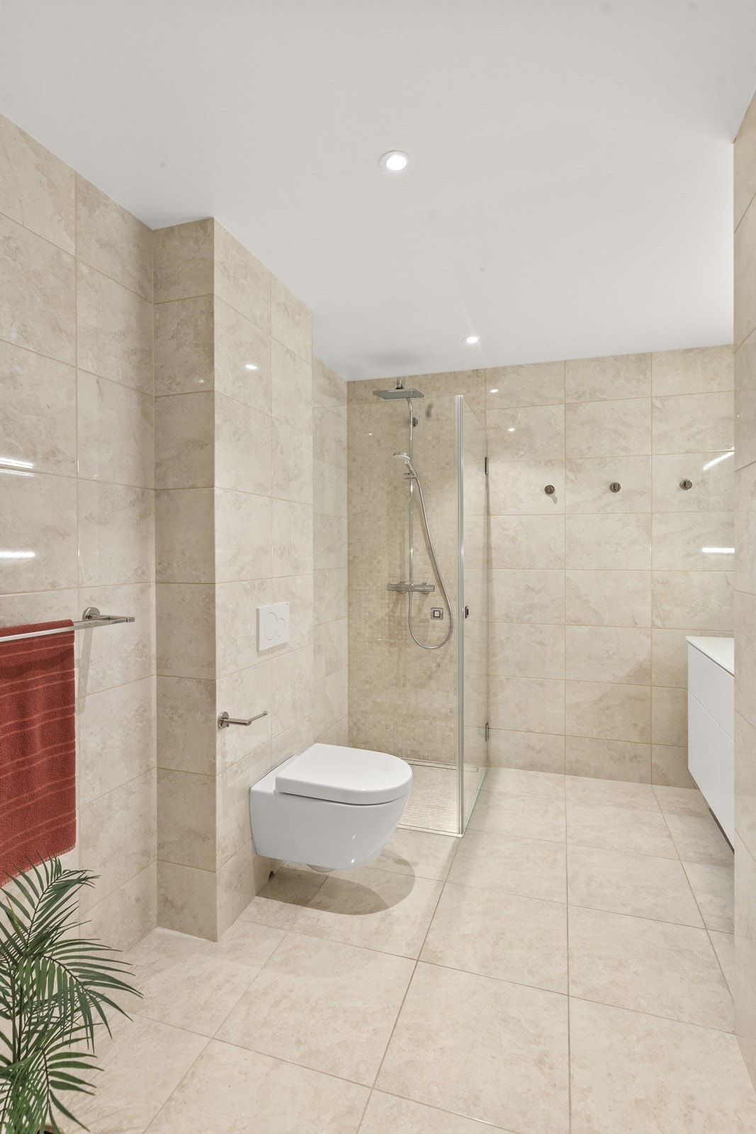 Helfliset bad med vegghengt toalett og romslig dusjhjørne med glassvegger. Galleribilde