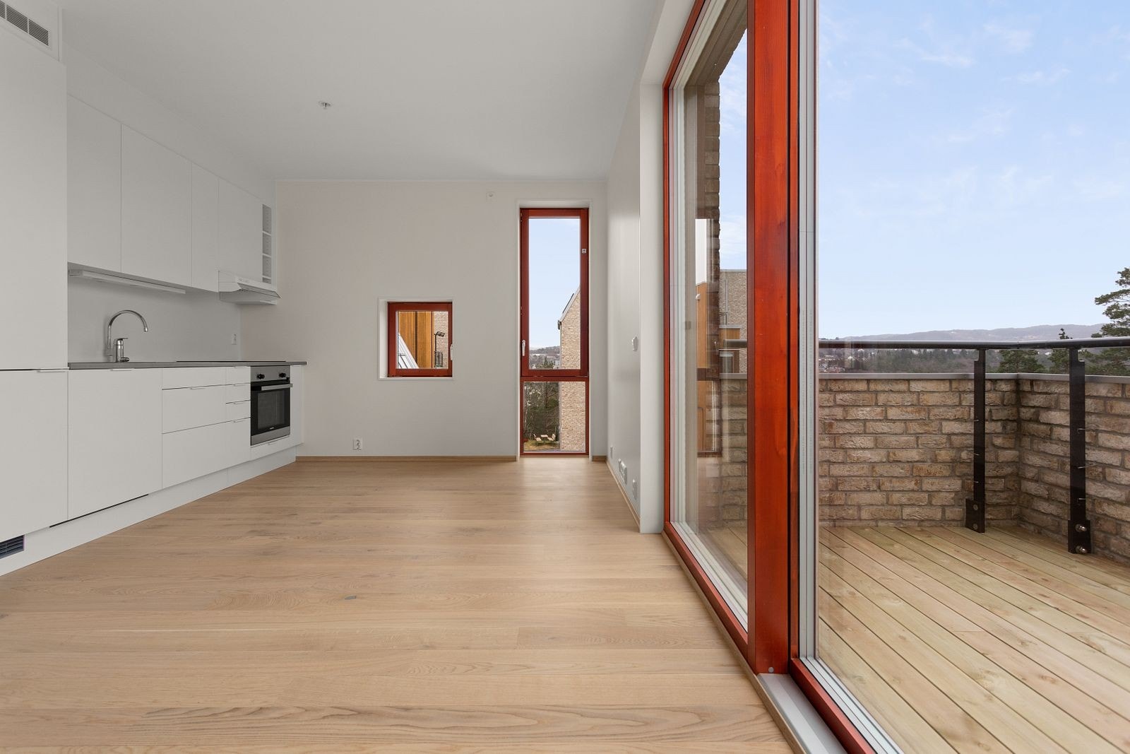 Åpen løsning fra kjøkken til stue, der store vindusflater sikrer godt med lys og god romfølelse Galleribilde