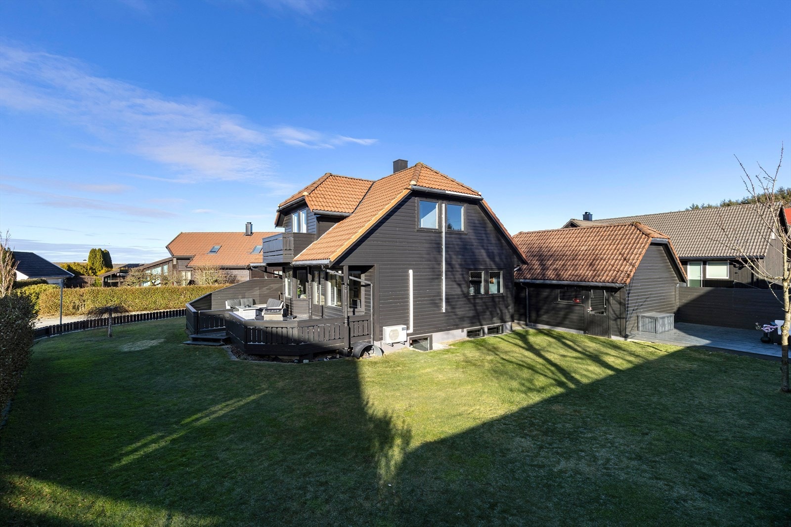 Stor hage som er pent rammet inn med gjerde, hekk og beplantning. Galleribilde