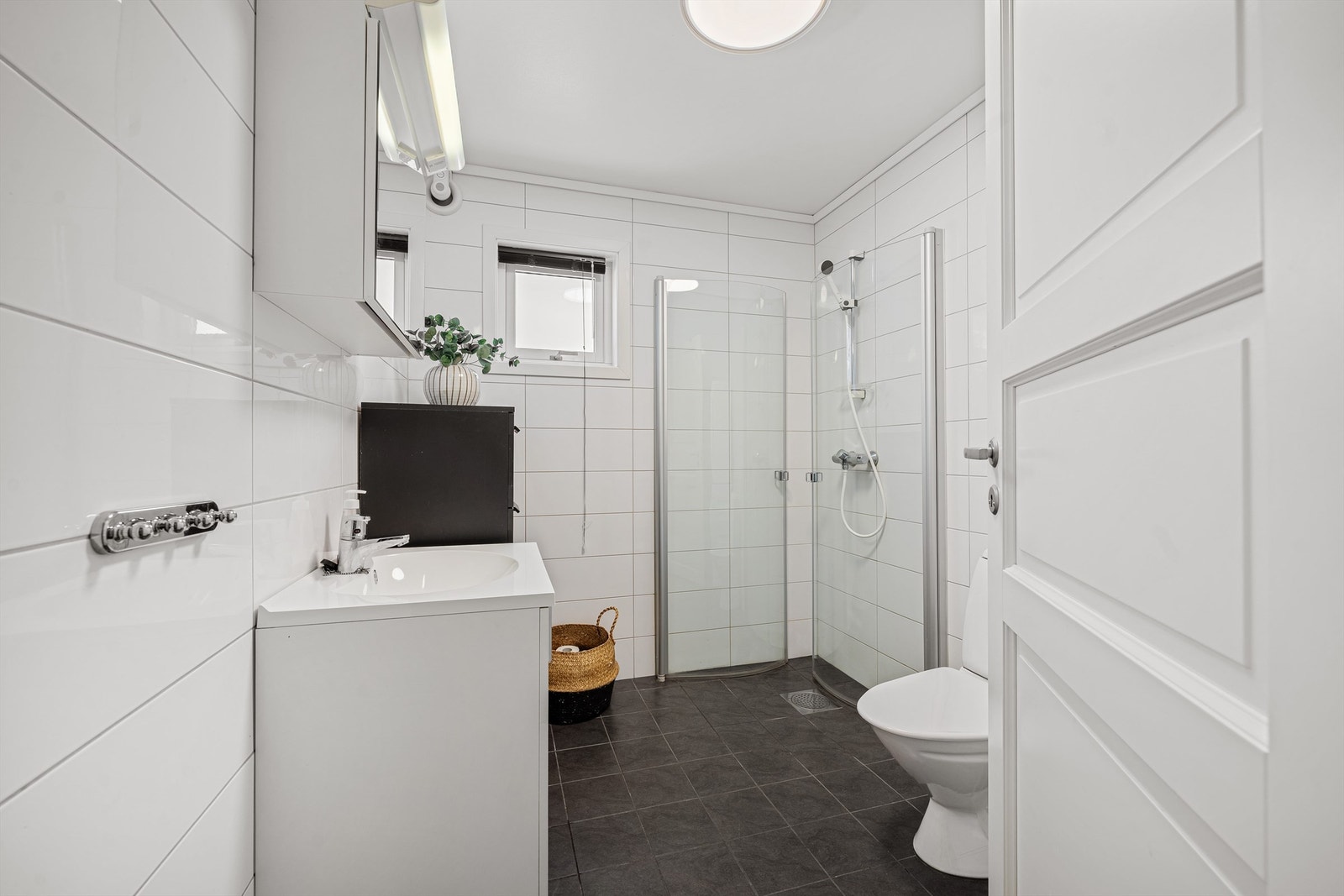 Innholdsrikt bad med dusjhjørne, innredning med servant og overskap Galleribilde