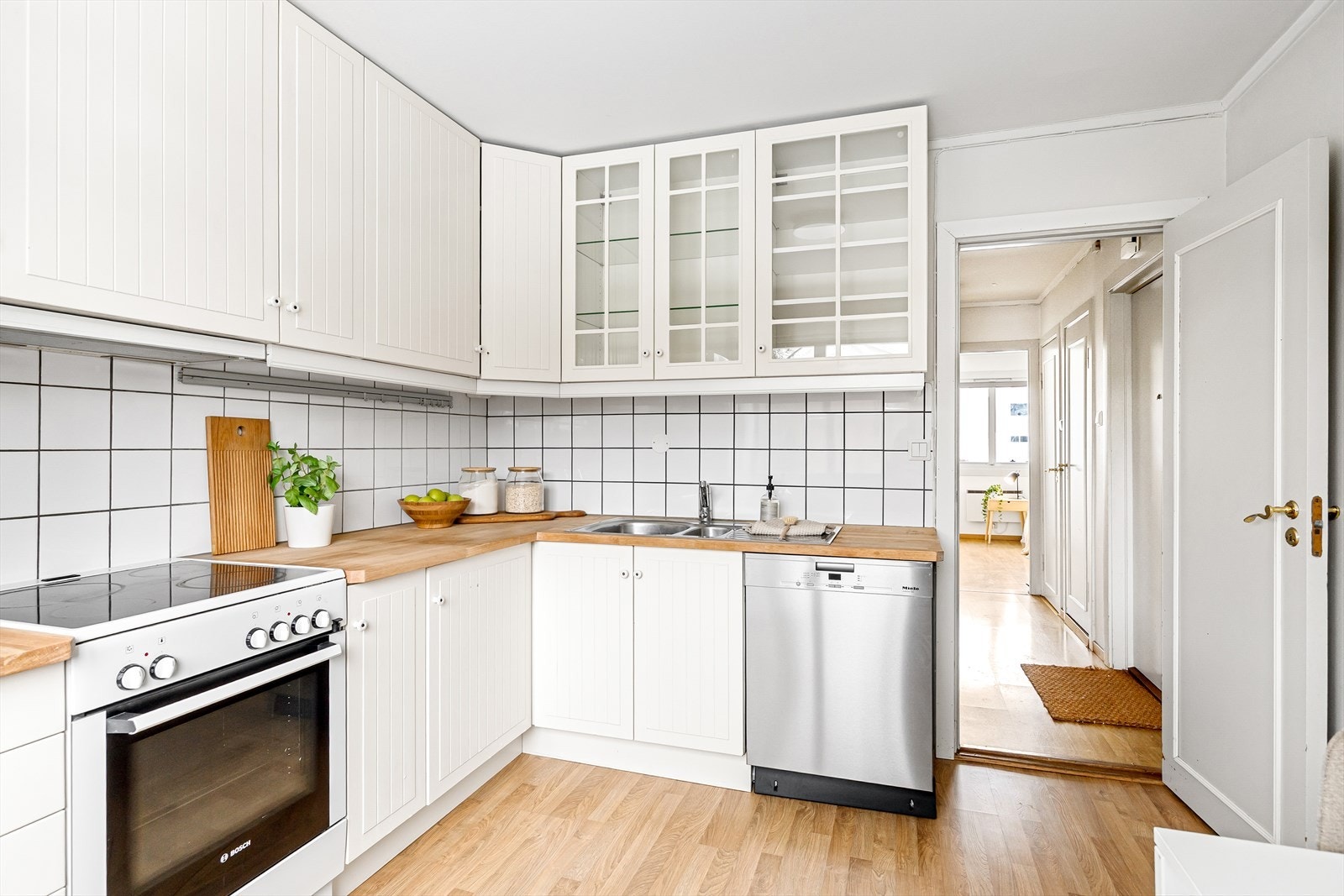 Hvite profilerte fronter og benkeplate i tre skaper et lyst og rent inntrykk på kjøkkenet. Galleribilde